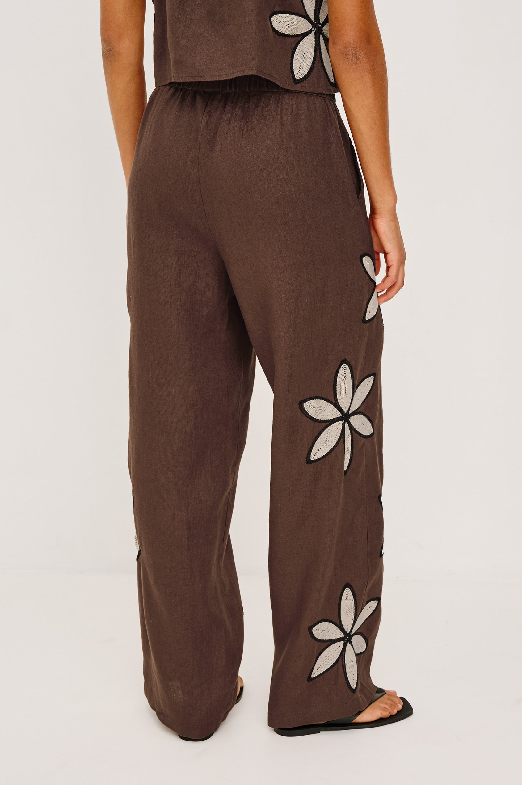Emmie Straight Leg Pant in Unlined Linen With Adjustable Drawstring Waist Ties and Side Pockets in Cocoa Floral Embroidery Colorway — Lower Body Back View Featured on Model
