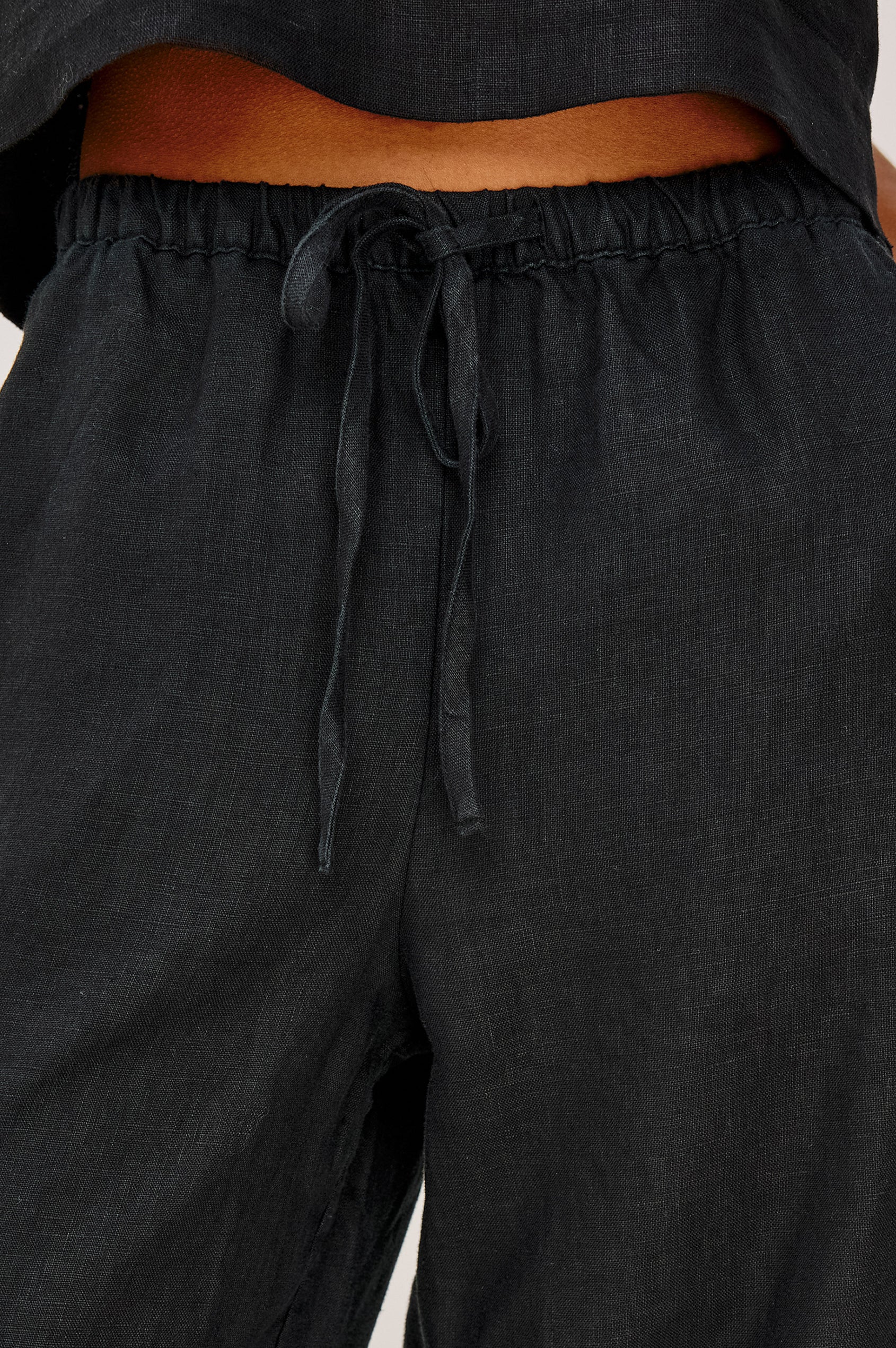 Emmie Crop Pant in Linen With Straight Legs, Adjustable Drawstring Waist Ties, and Side Pockets in Black Linen Colorway - Lower Body Back View Featured on Model