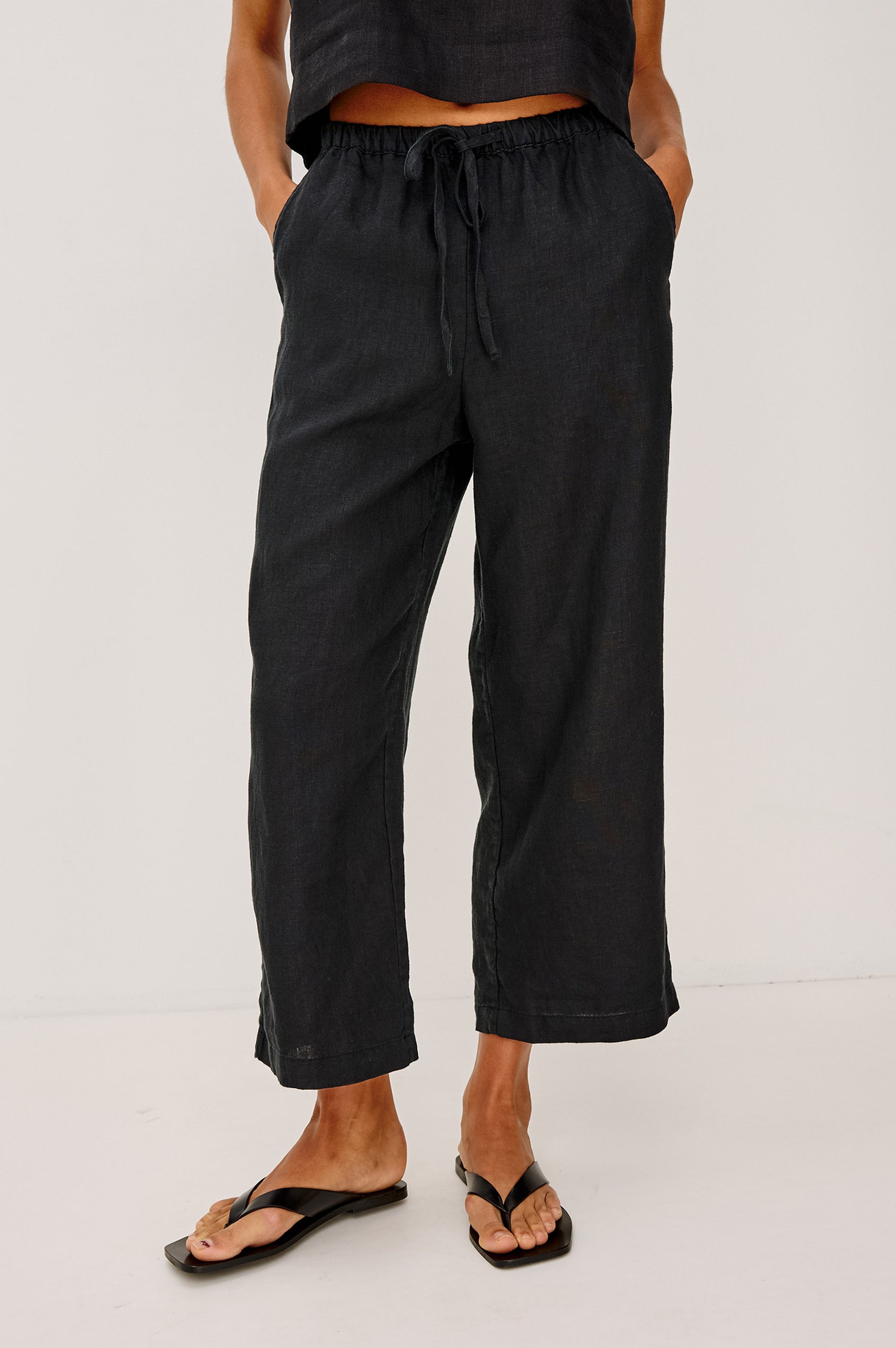 Emmie Crop Pant in Linen With Straight Legs, Adjustable Drawstring Waist Ties, and Side Pockets in Black Linen Colorway - Lower Body Front View Featured on Model