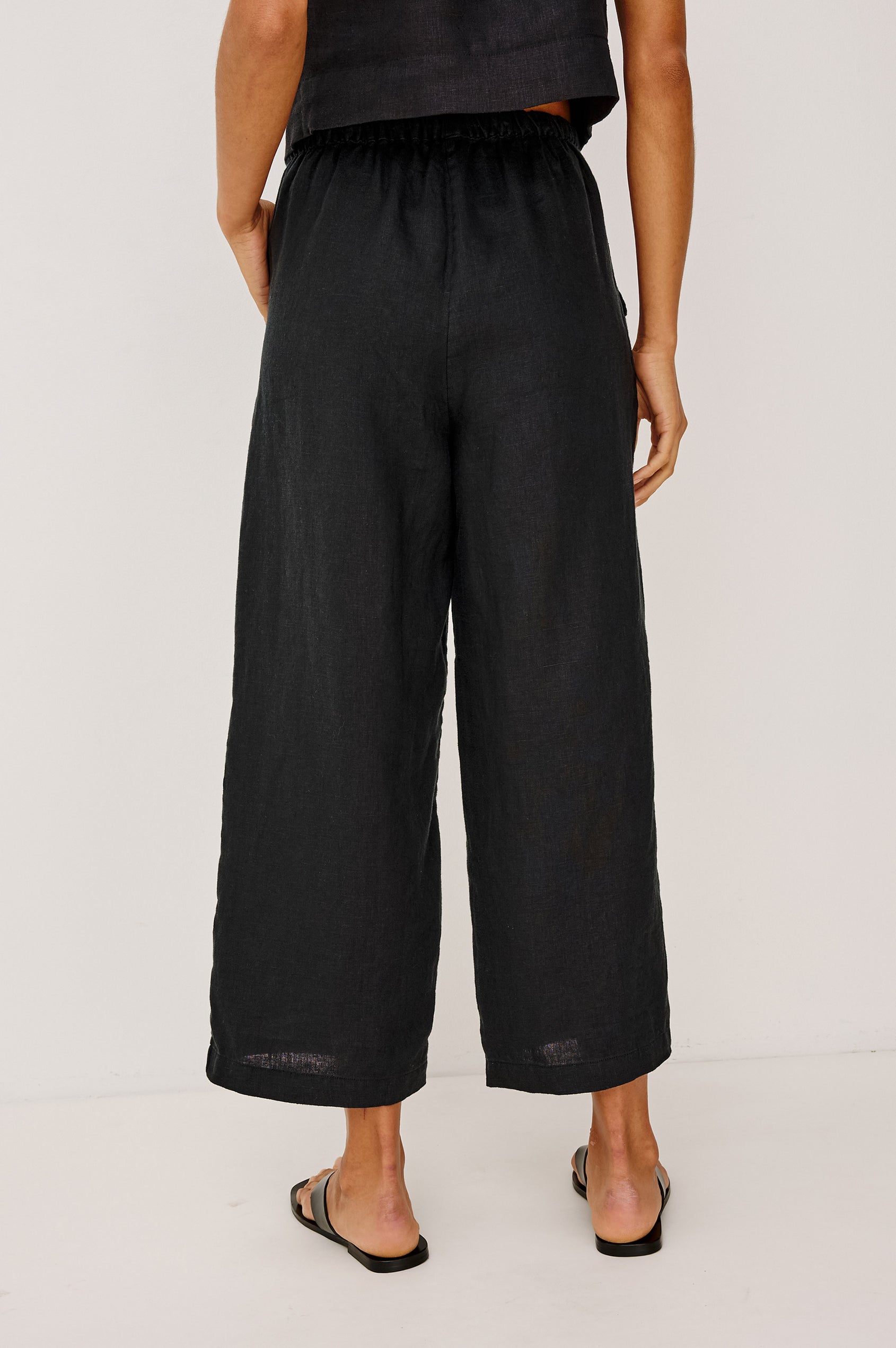 Emmie Crop Pant in Linen With Straight Legs, Adjustable Drawstring Waist Ties, and Side Pockets in Black Linen Colorway - Lower Body Back View Featured on Model