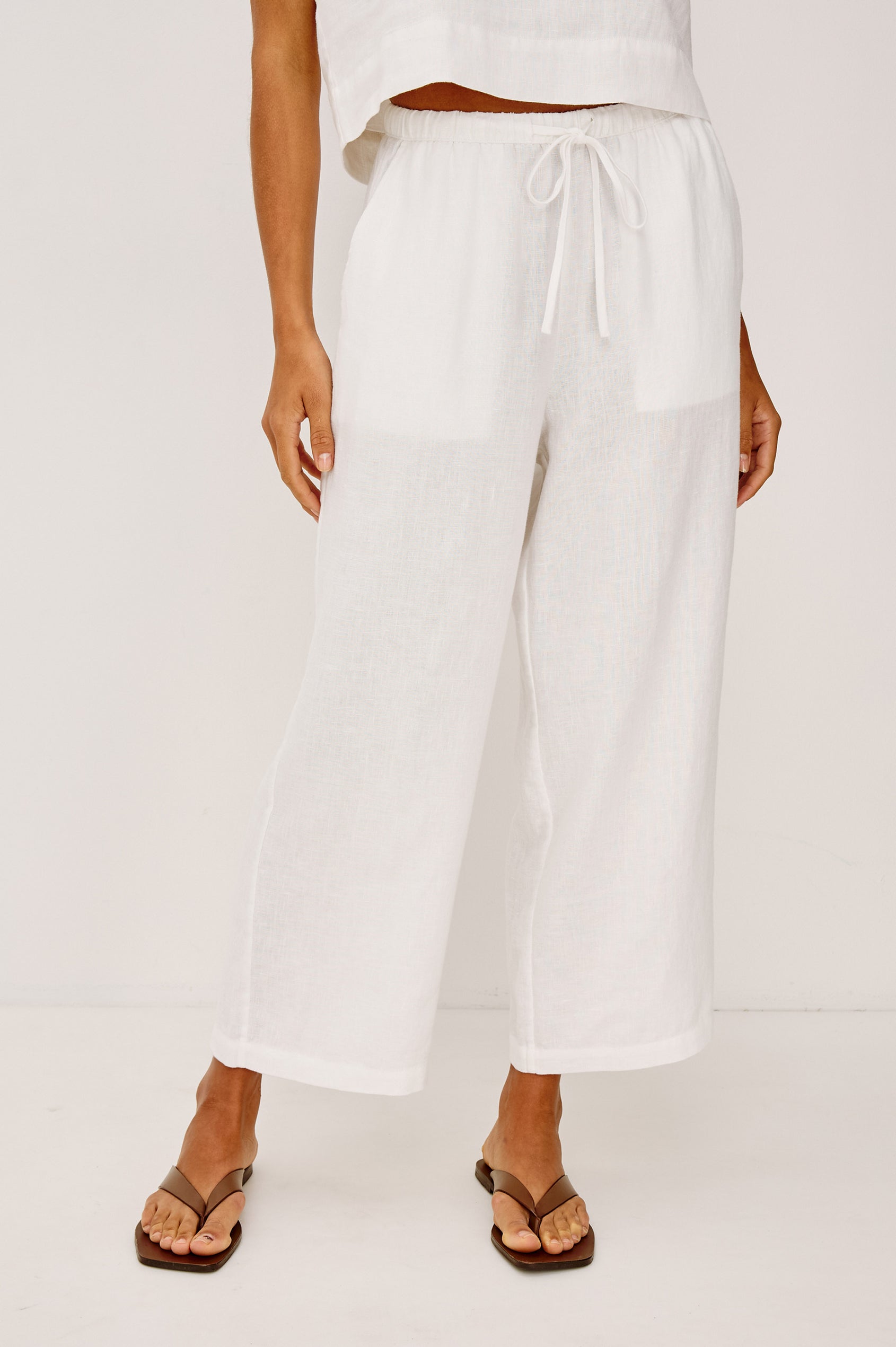 Emmie Crop Pant in Linen With Straight Legs, Adjustable Drawstring Waist Ties, and Side Pockets in White Linen Colorway - Lower Body Front View Featured on Model