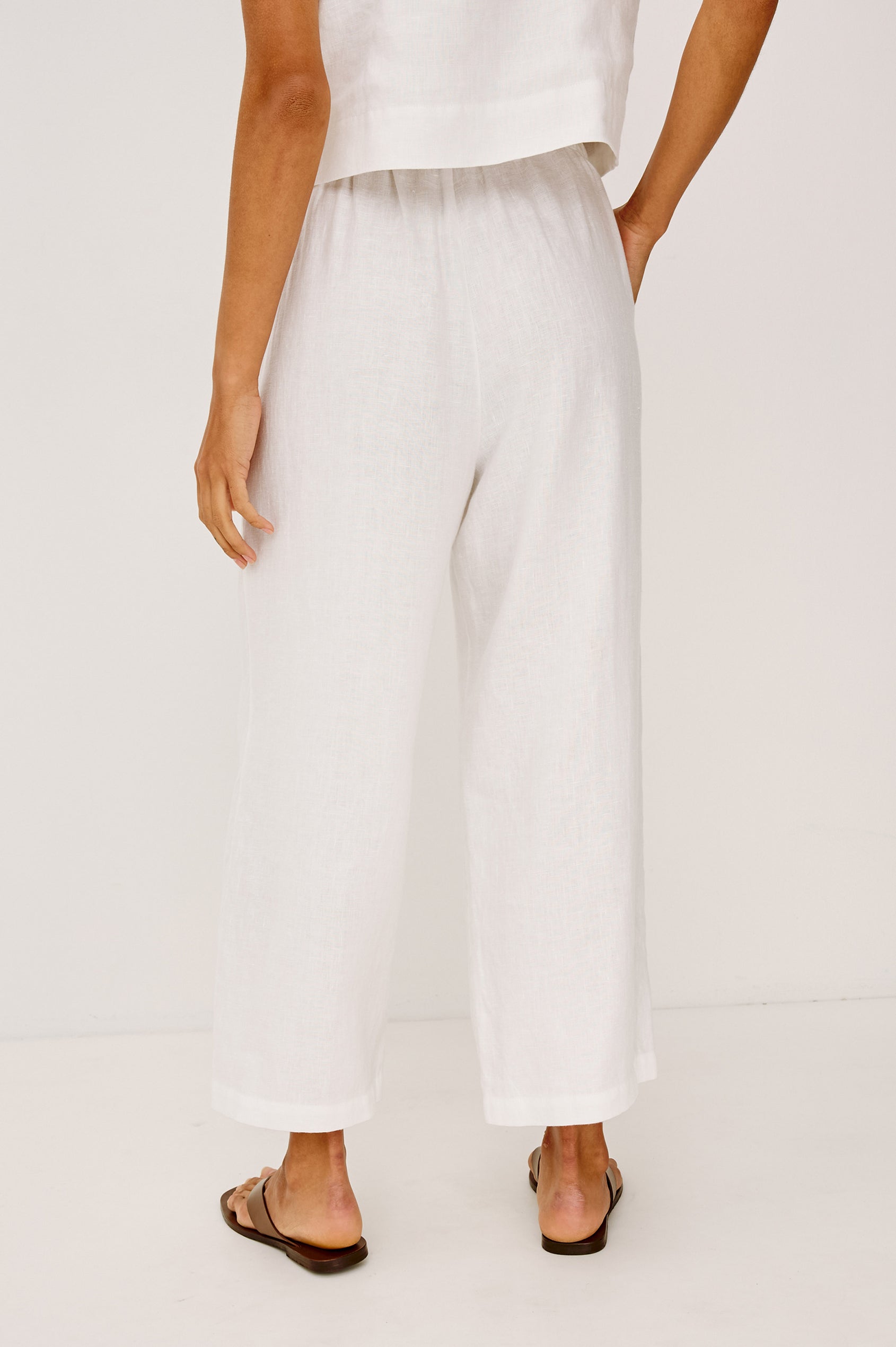 Emmie Crop Pant in Linen With Straight Legs, Adjustable Drawstring Waist Ties, and Side Pockets in White Linen Colorway - Lower Body Back View Featured on Model