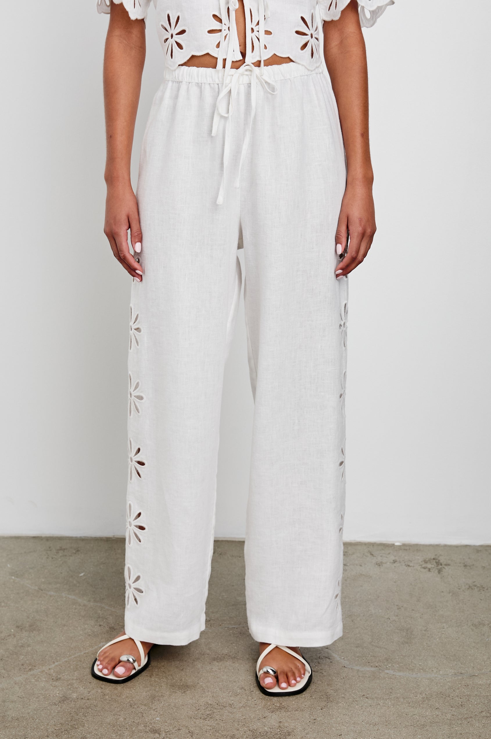 Emmie Pants with a Drawstring Waist and Two Front Pockets in White Eyelet Colorway, with eyelets along the outer sides - Front View Featured on Model