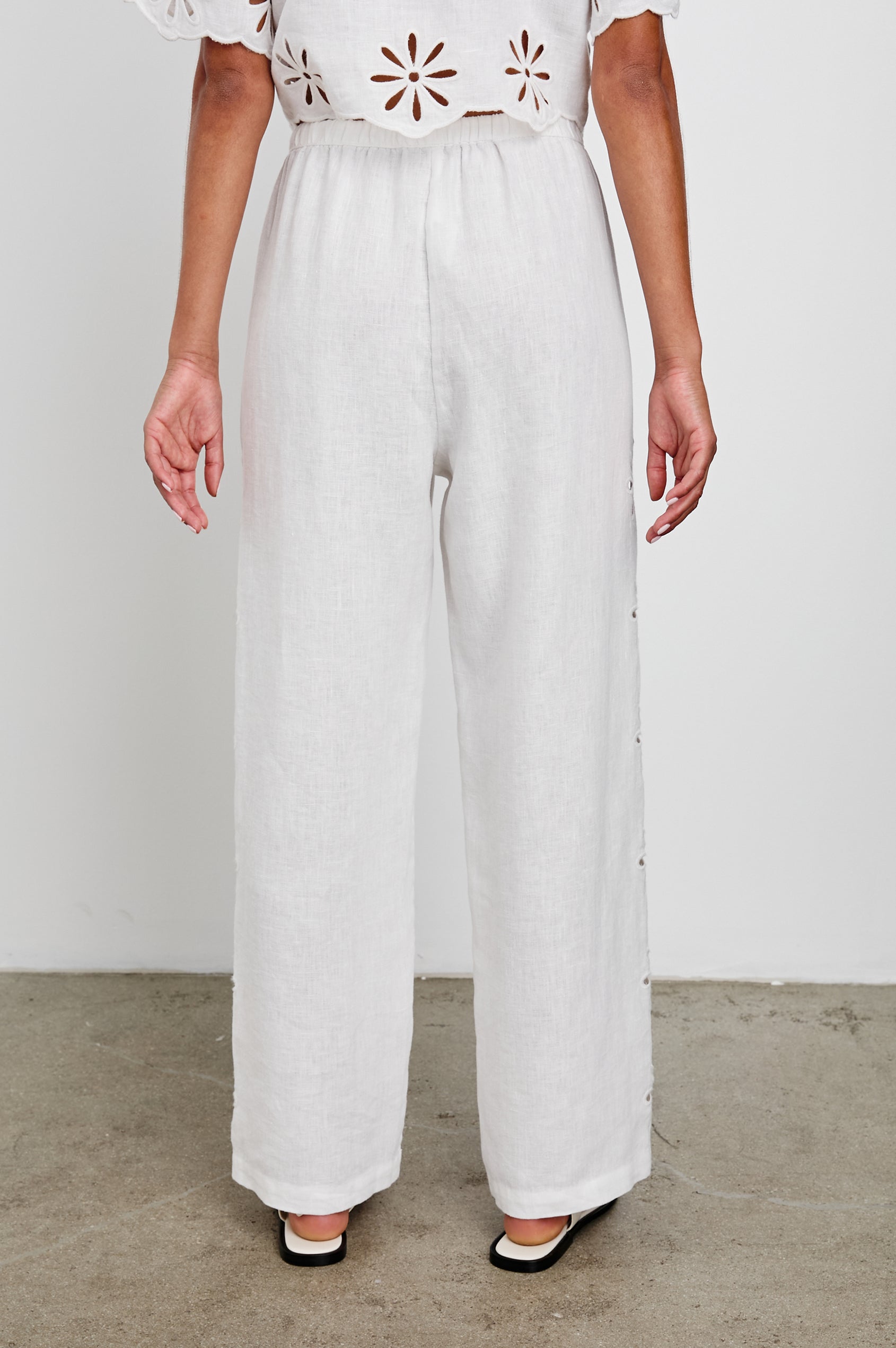 Emmie Pants with a Drawstring Waist and Two Front Pockets in White Eyelet Colorway, with eyelets along the outer sides - Back View Featured on Model