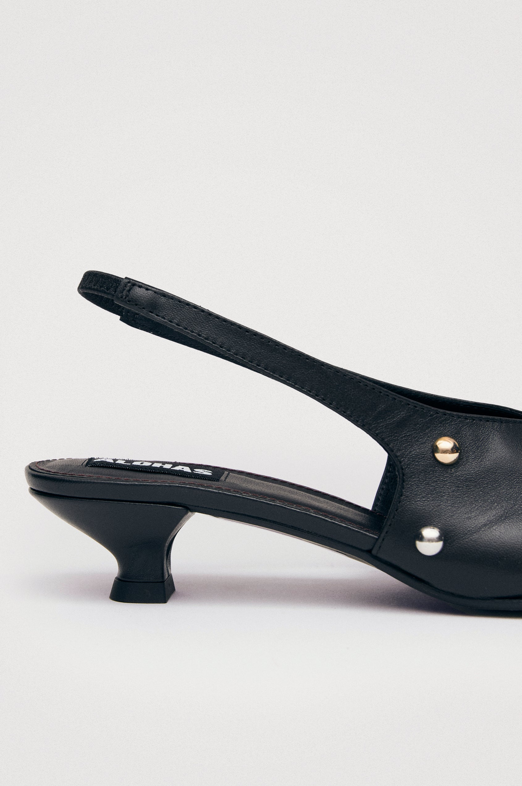 Crinkled leather slingback pump with elastic strap, pointed toe, and minimalist long vamp. Close up of heel details.