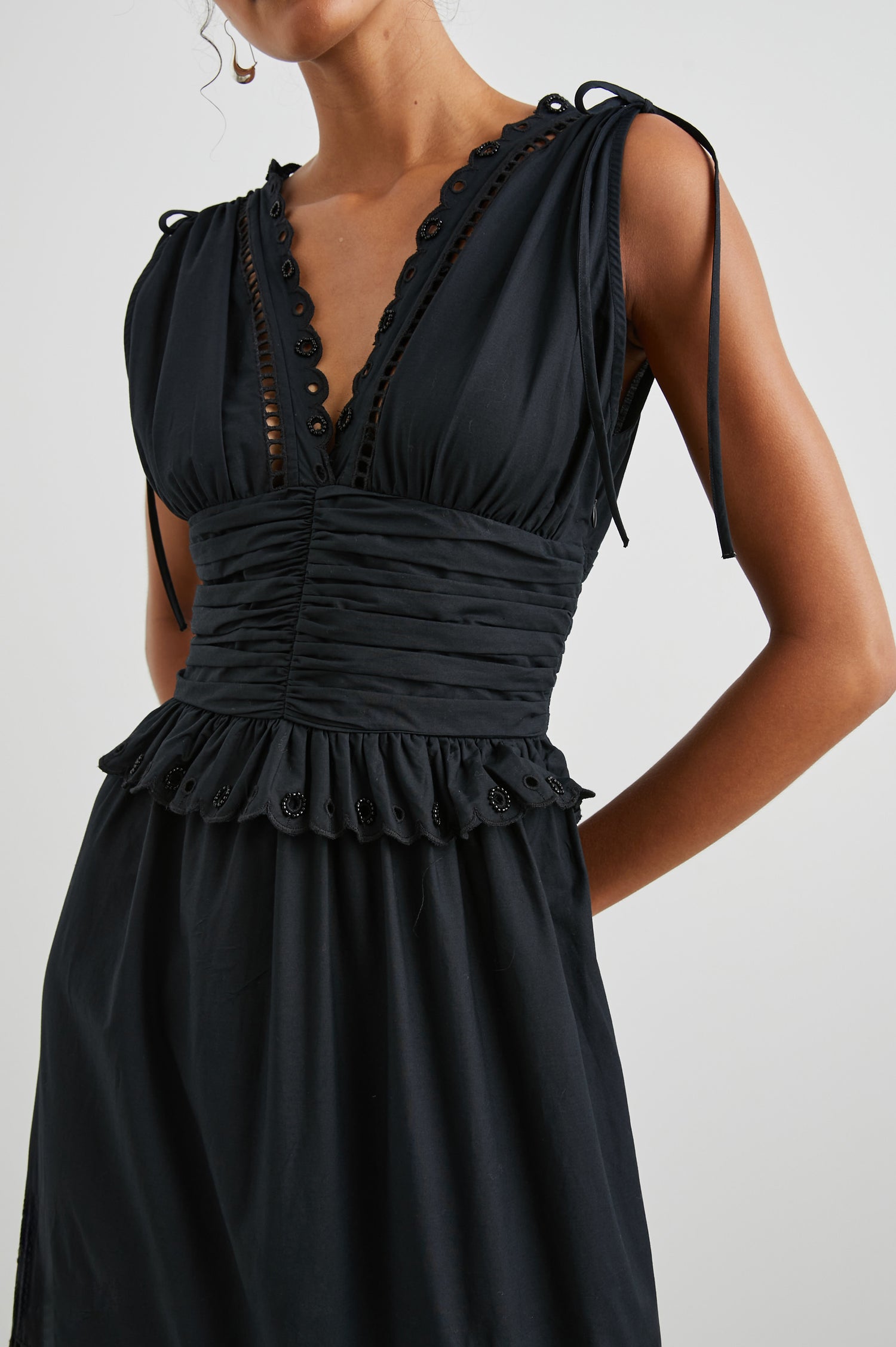 Esmeralda Sleeveless Maxi Dress with a Deep V Neck, a Ruched Waistband, Drawstrings Across the Shoulder Straps, Scalloped Trim with Cutouts on the Bodice, a Tiered Skirt, and an Eyelet Design along the Hem in Black Colorway - Front View Featured on Model 