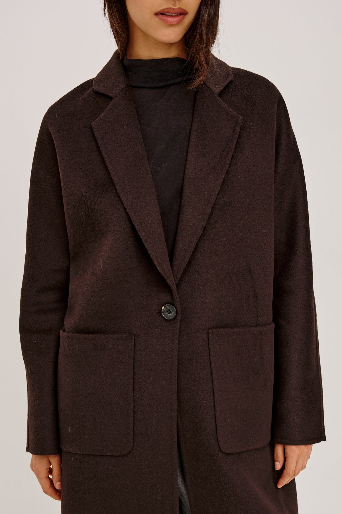 Everest Coat in Heavy Wool Blend With Longline Cut, Slightly Oversized Relaxed Fit, Lapel Collar, Single-Button Front, and Front Patch Pockets in Chocolate Colorway - Upper Body Front Detail View Featured on Model.
