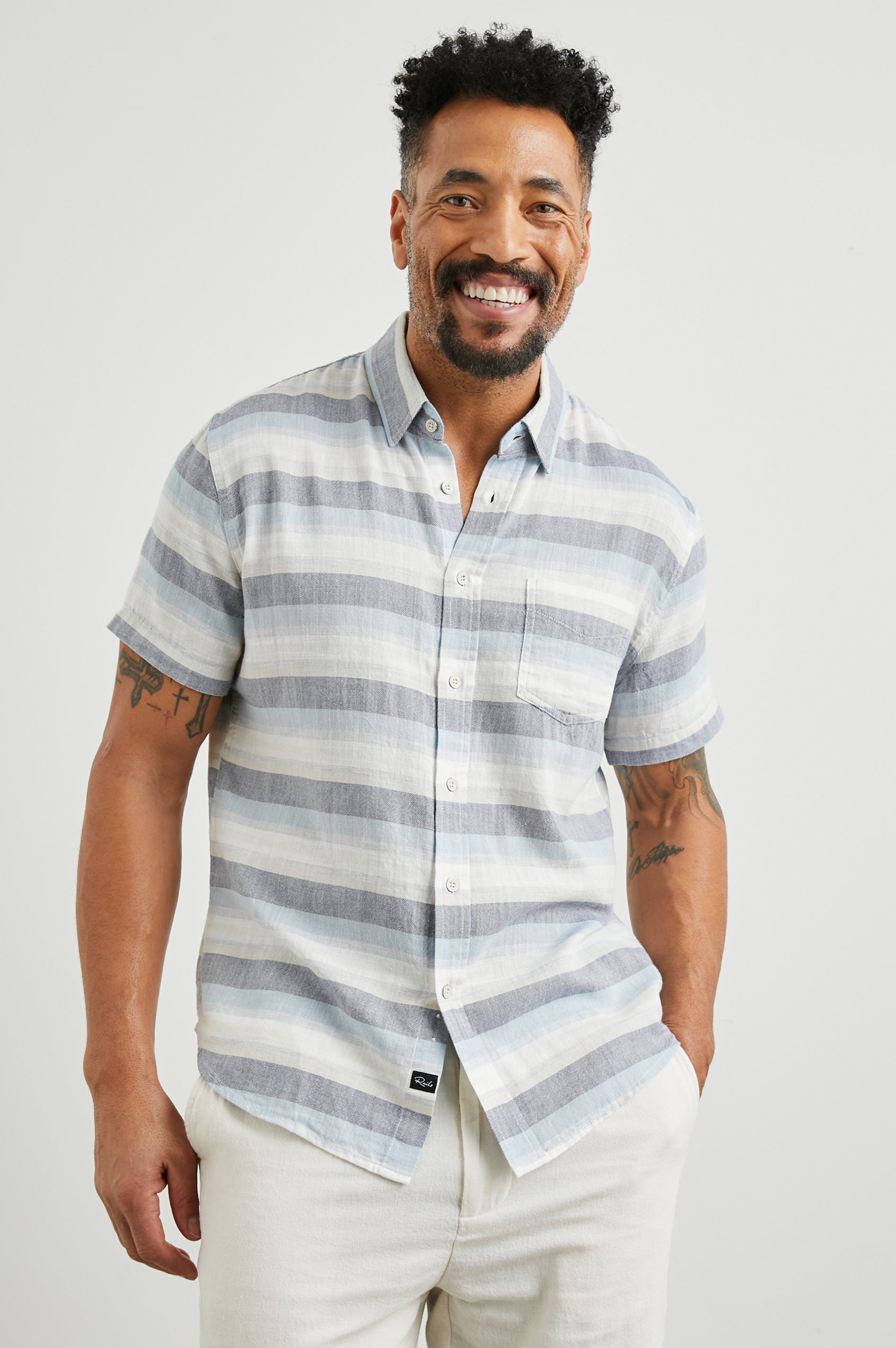 Fairfax Short-Sleeve Button Up with a Chest Patch Pocket in Tabernas Shadow Colorway, with light grey, dark grey, blue and white horizontal stripes - Front View Featured on Model