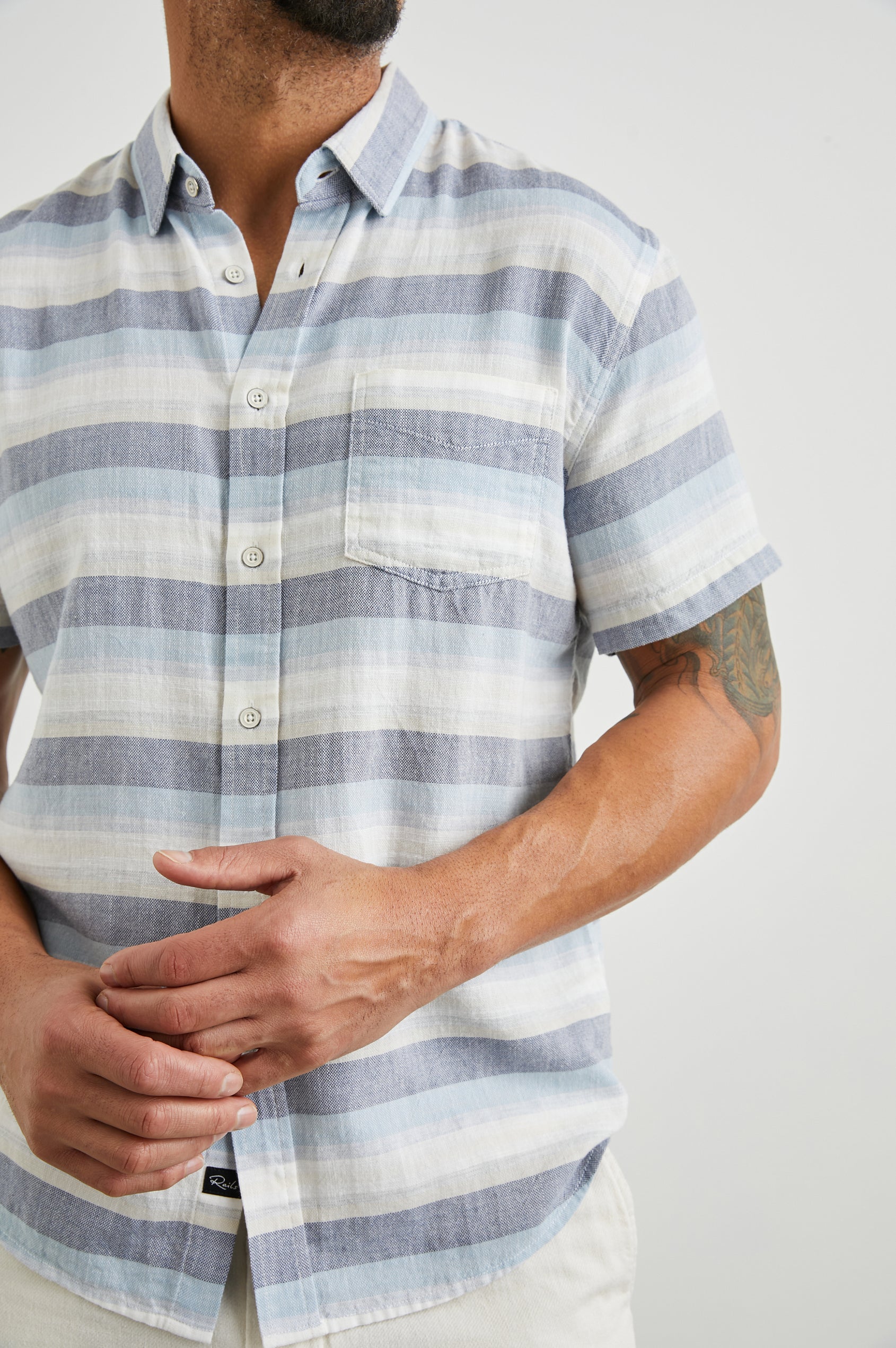 Fairfax Short-Sleeve Button Up with a Chest Patch Pocket in Tabernas Shadow Colorway, with light grey, dark grey, blue and white horizontal stripes - Front View Featured on Model