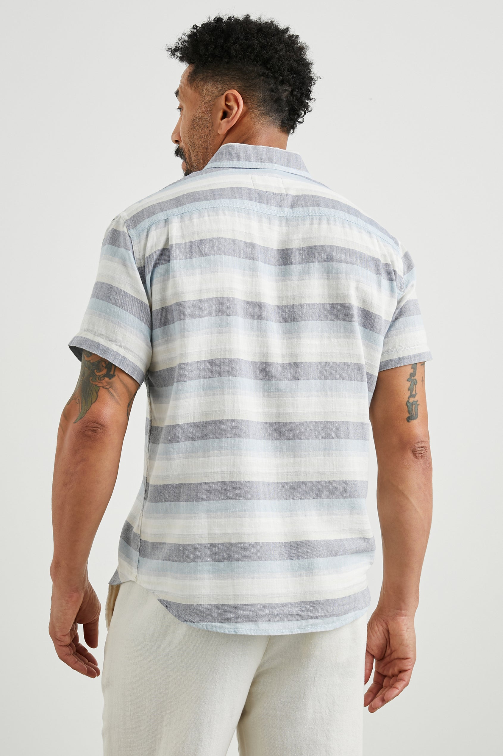 Fairfax Short-Sleeve Button Up with a Chest Patch Pocket in Tabernas Shadow Colorway, with light grey, dark grey, blue and white horizontal stripes - Back View Featured on Model