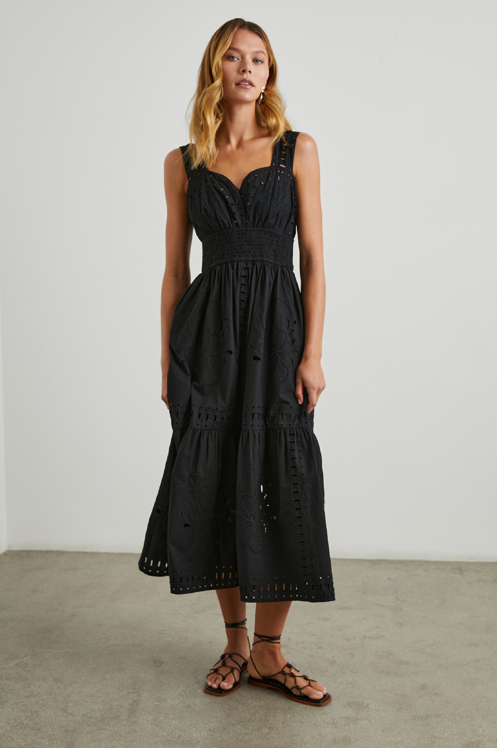 Fawn Sleeveless Midi Dress with Wide Straps, a Sweetheart Neckline, a Cinched Waist and Floral and Geometric Eyelet Details in Black Colorway - Front Full Body View Featured on Model
