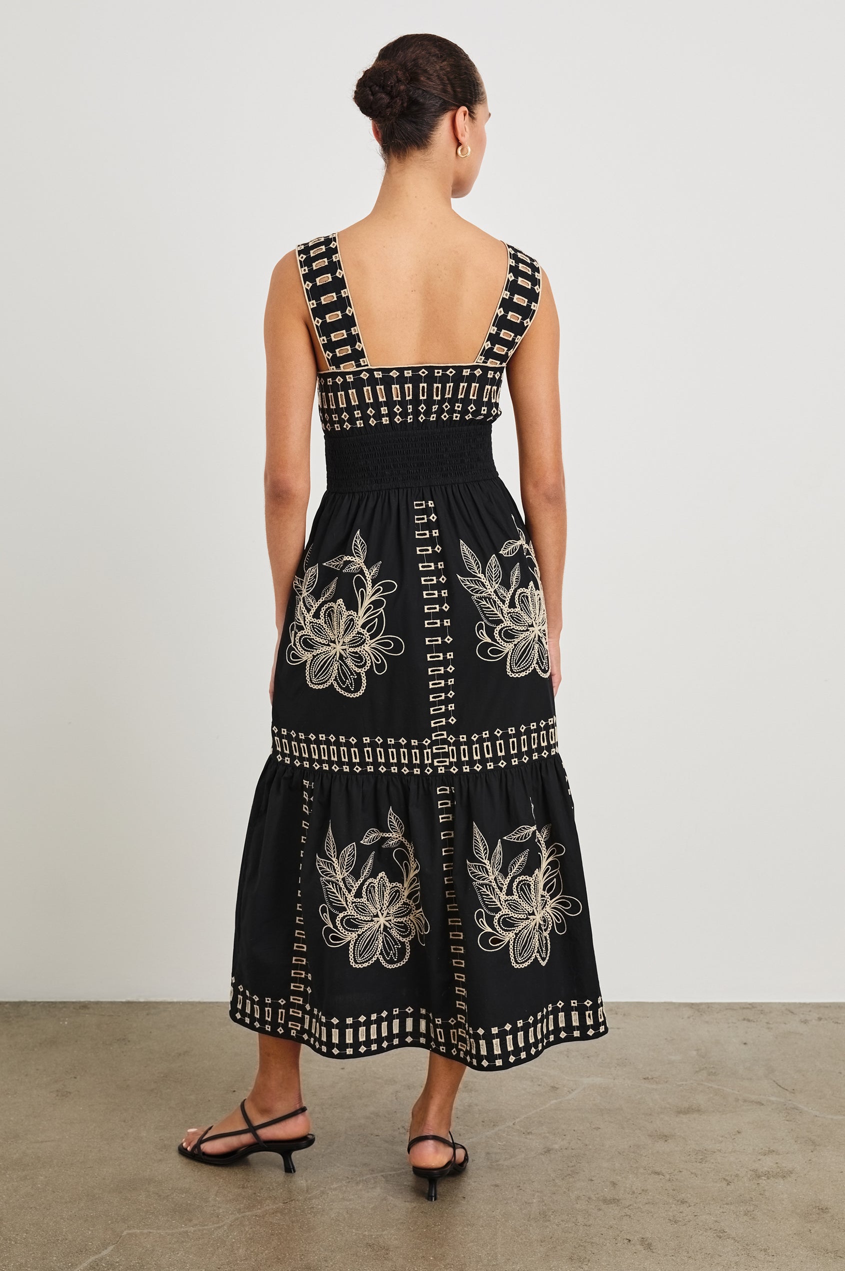 Back view of model wearing our sleeveless, Fawn Midi Dress with Black Tan Embroidery contrast and eyelet details. 