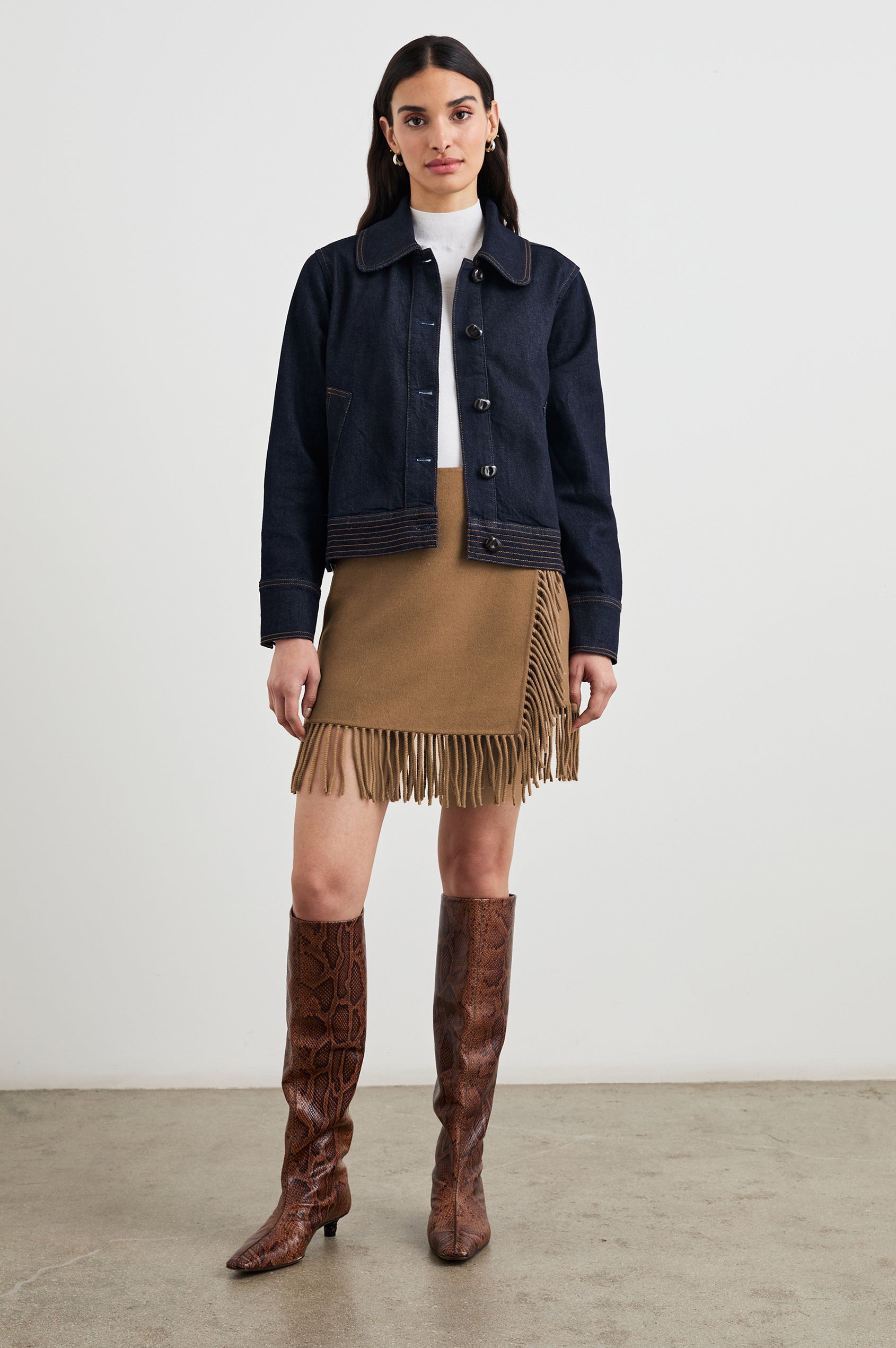 Figueroa Denim Jacket with Button Closure, Two Front Pockets, Adjustable Hem Buckle Tabs and Gold Toned Seam Stitching in Midnight Blues Colorway - Front Full Body View Featured on Model