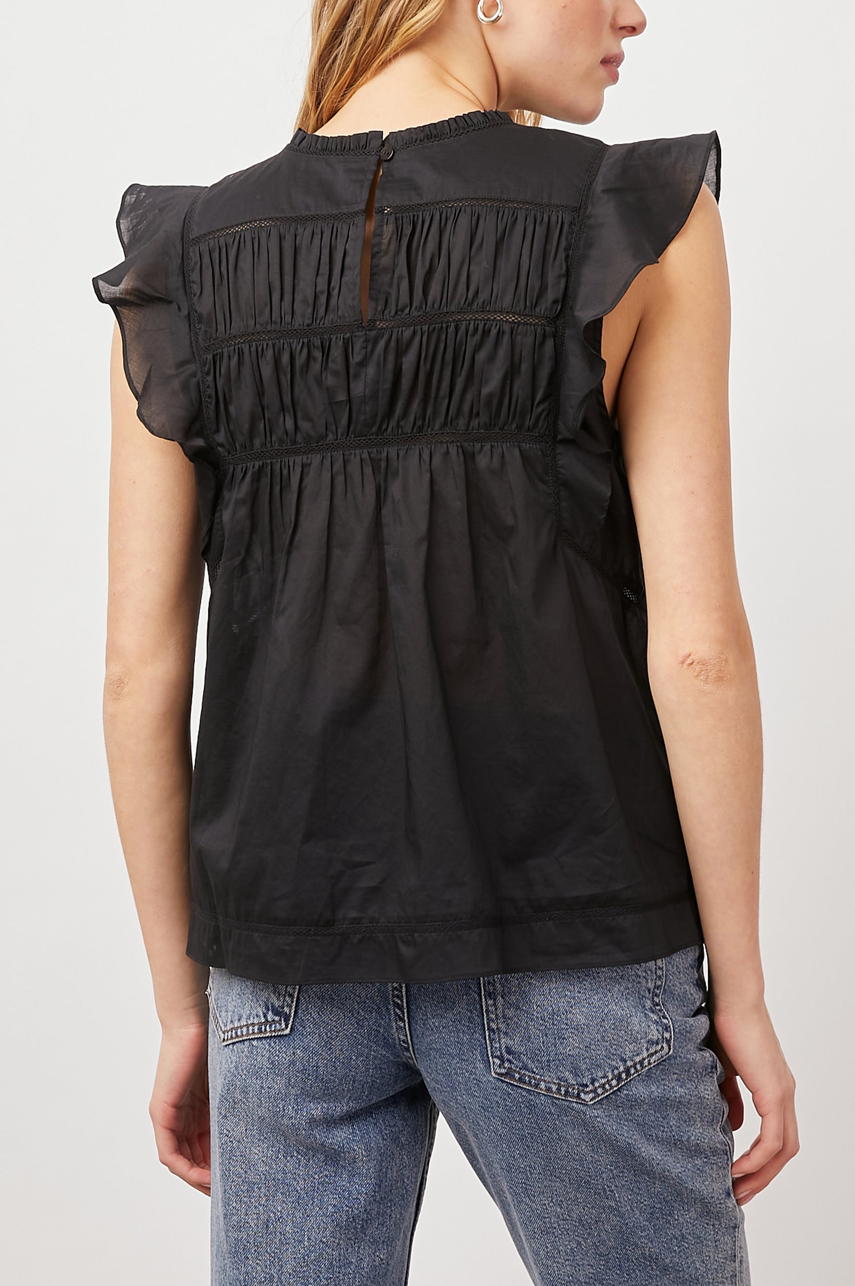 Filomena Short Sleeve Top with Flutter Sleeves, a Ruffled Neck, a Shirred Center Bodice, Lace Inserts and a Buttoned Keyhole at the Back in True Black Colorway - Back View Featured on Model