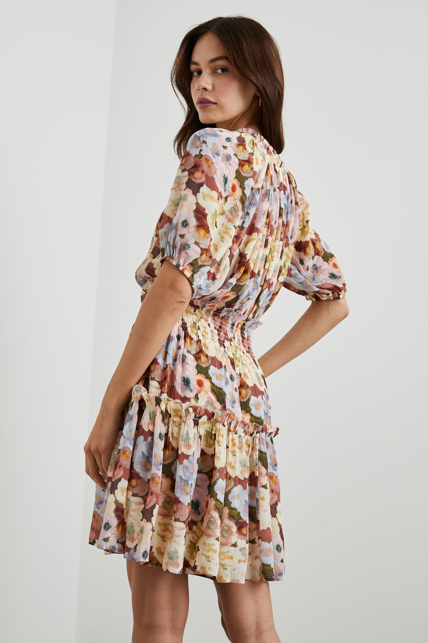 Fiorella Short-Sleeve, Above-Knee Dress with a Shirred Collar and Waist, V-neckline with Ties, Puff Sleeves and a Tiered Skirt in Painted Floral Colorway, with browns, yellows and blues - Back View Featured on Model