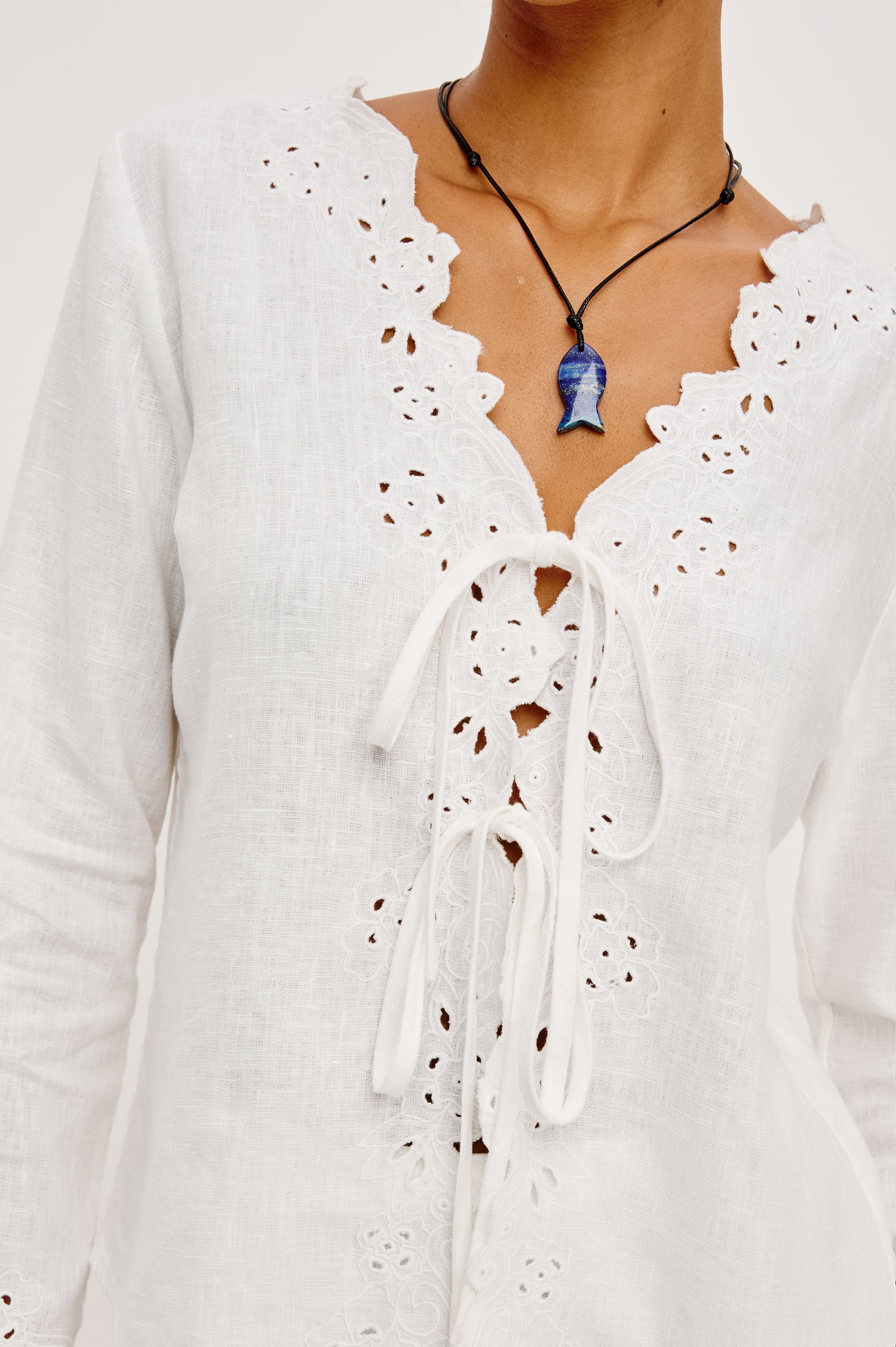 Fleur Top in Linen With Floral Eyelet Embroidery Open Front Adjustable Front Self-Ties Long Sleeves and Loose Fit in White - Upper Body Close Up Front View Featured on Model