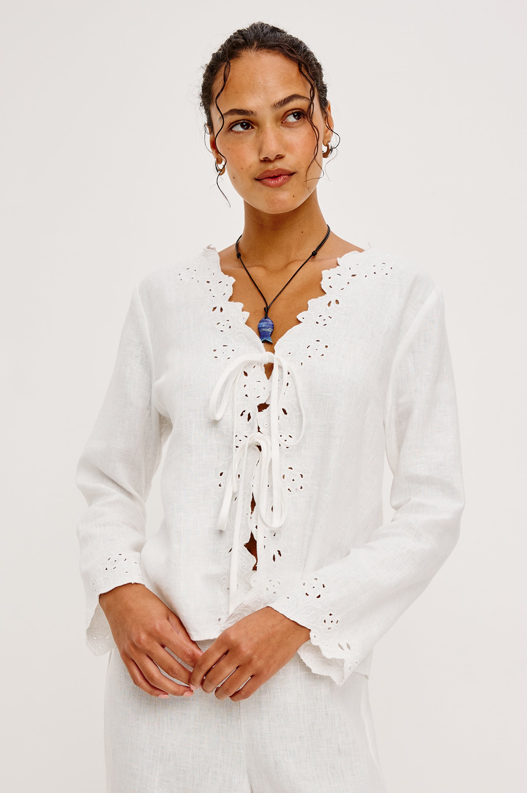 Fleur Top in Linen With Floral Eyelet Embroidery Open Front Adjustable Front Self-Ties Long Sleeves and Loose Fit in White - Upper Body Front View Featured on Model