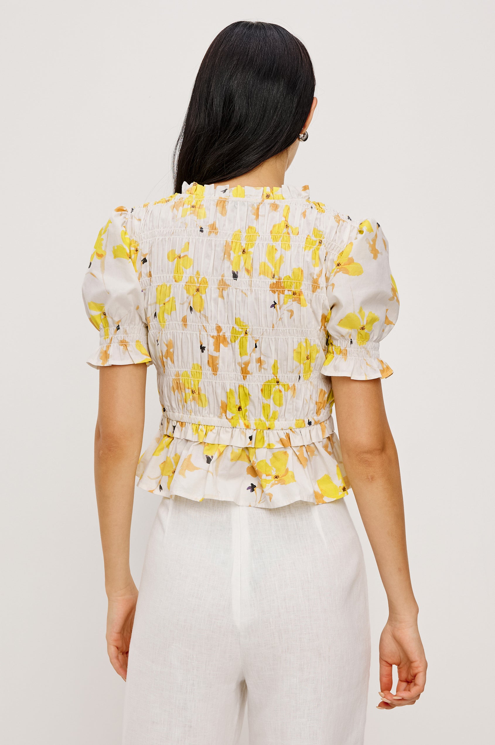 Fontaine Cropped Top in Cotton Poplin With Fitted Smocked Body V-Neckline With Center-Front Ties Short Puff Sleeves Rufle Trim and Peplum Hem in Tossed Daffodils Colorway - Upper Body Back View Featured on Model