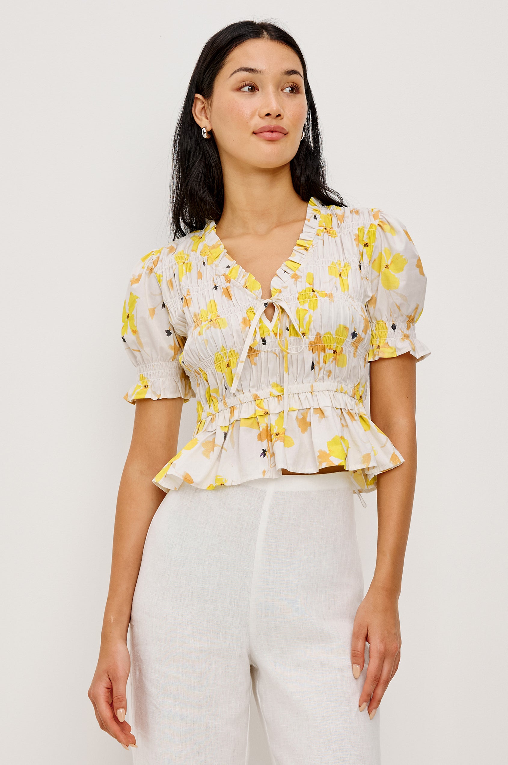 Fontaine Cropped Top in Cotton Poplin With Fitted Smocked Body V-Neckline With Center-Front Ties Short Puff Sleeves Rufle Trim and Peplum Hem in Tossed Daffodils Colorway - Upper Body Front View Featured on Model