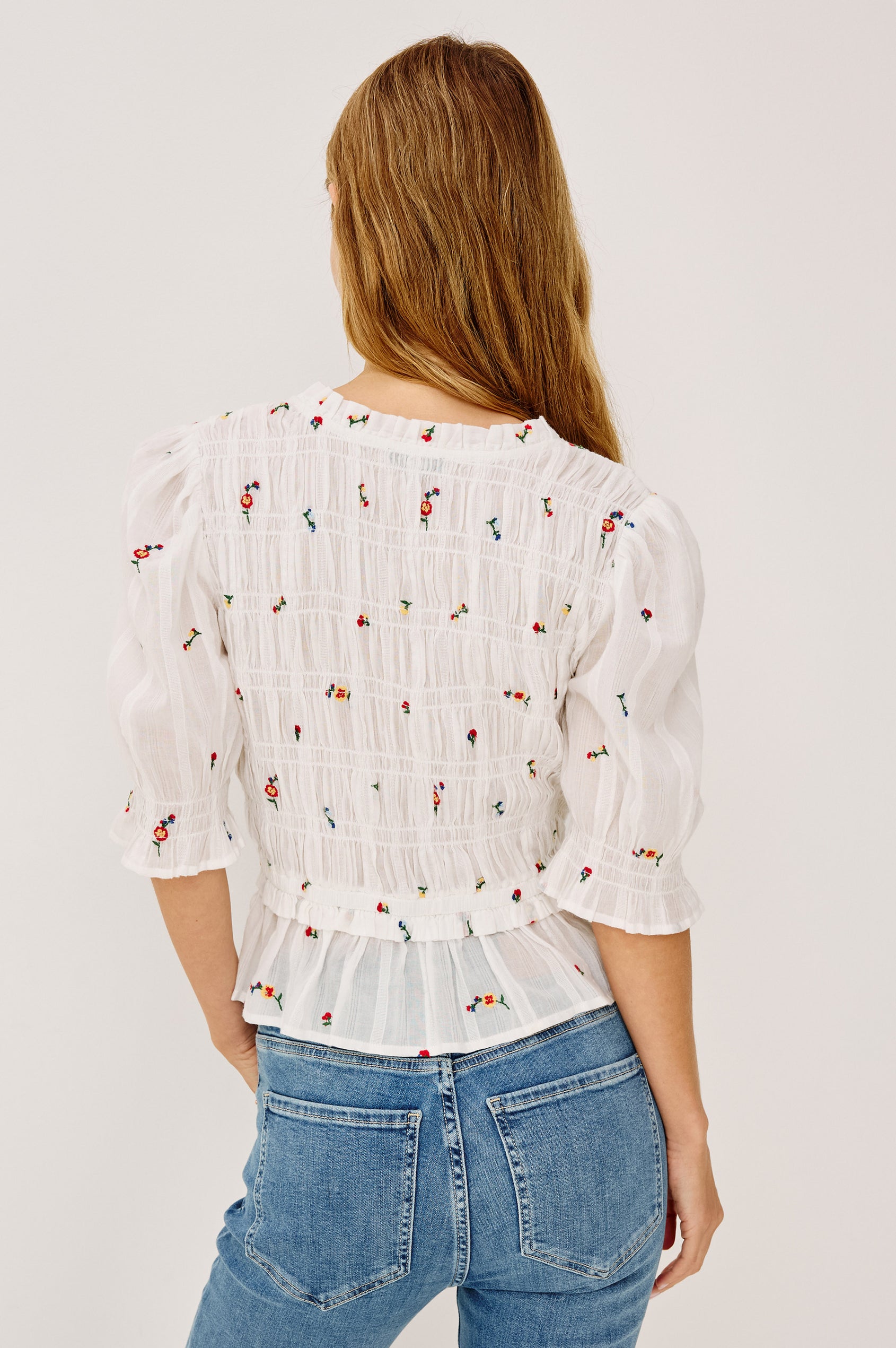 Fontaine Top in Cotton With Smocked Bodice, Self-Tie V-Neckline, Short Puff Sleeves, and Softly Flared Peplum Hem in White Wildflowers Colorway - Upper Body Back View Featured on Model