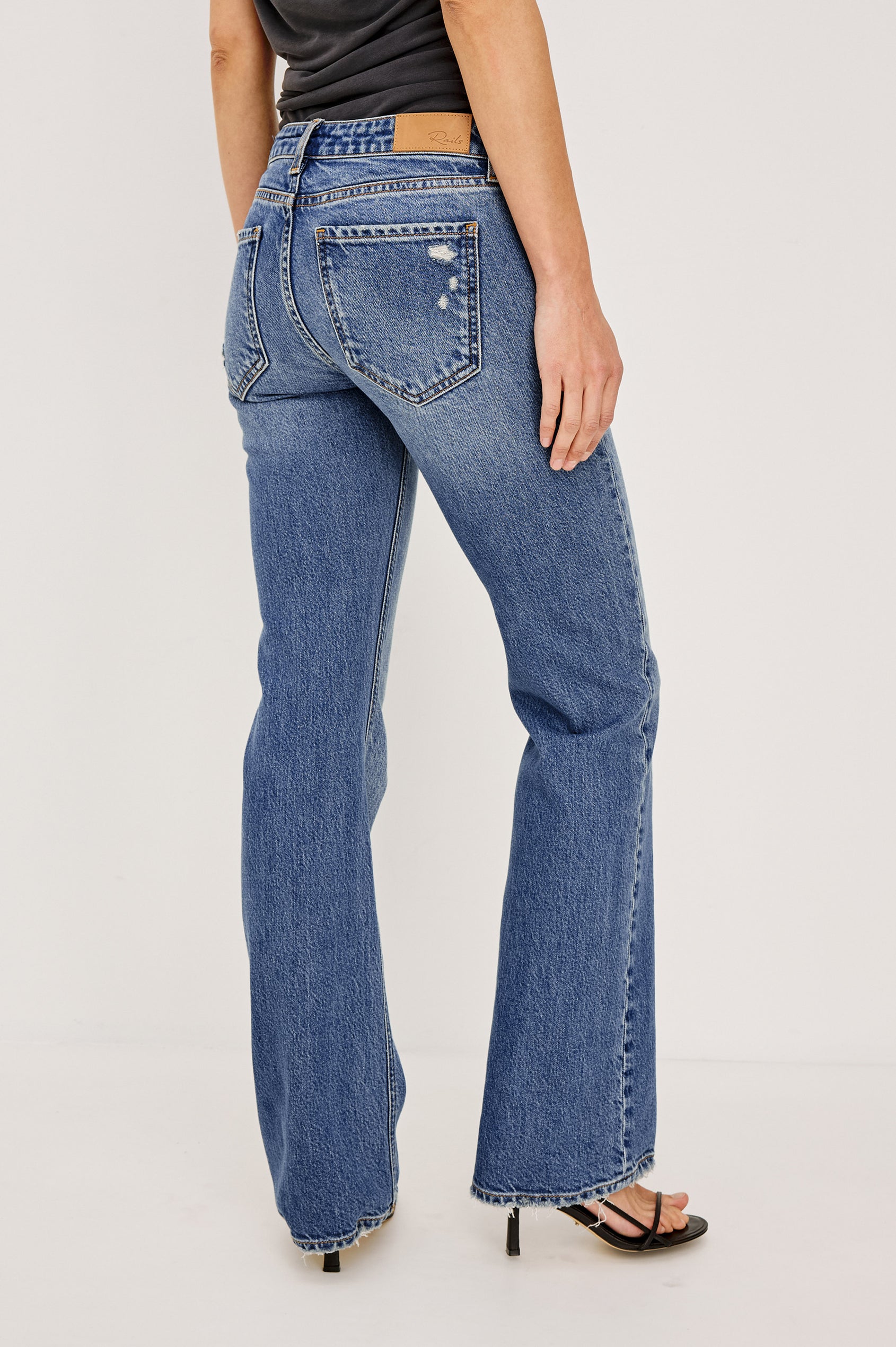 Fremont Low Rise Bootcut Jean in Light Stretch Denim With Extended Inseam, 5-Pockets, Distressed Details, Belt Loops, and Zip-Fly Closure in Pioneertown Colorway - Lower Body Back View Featured on Model