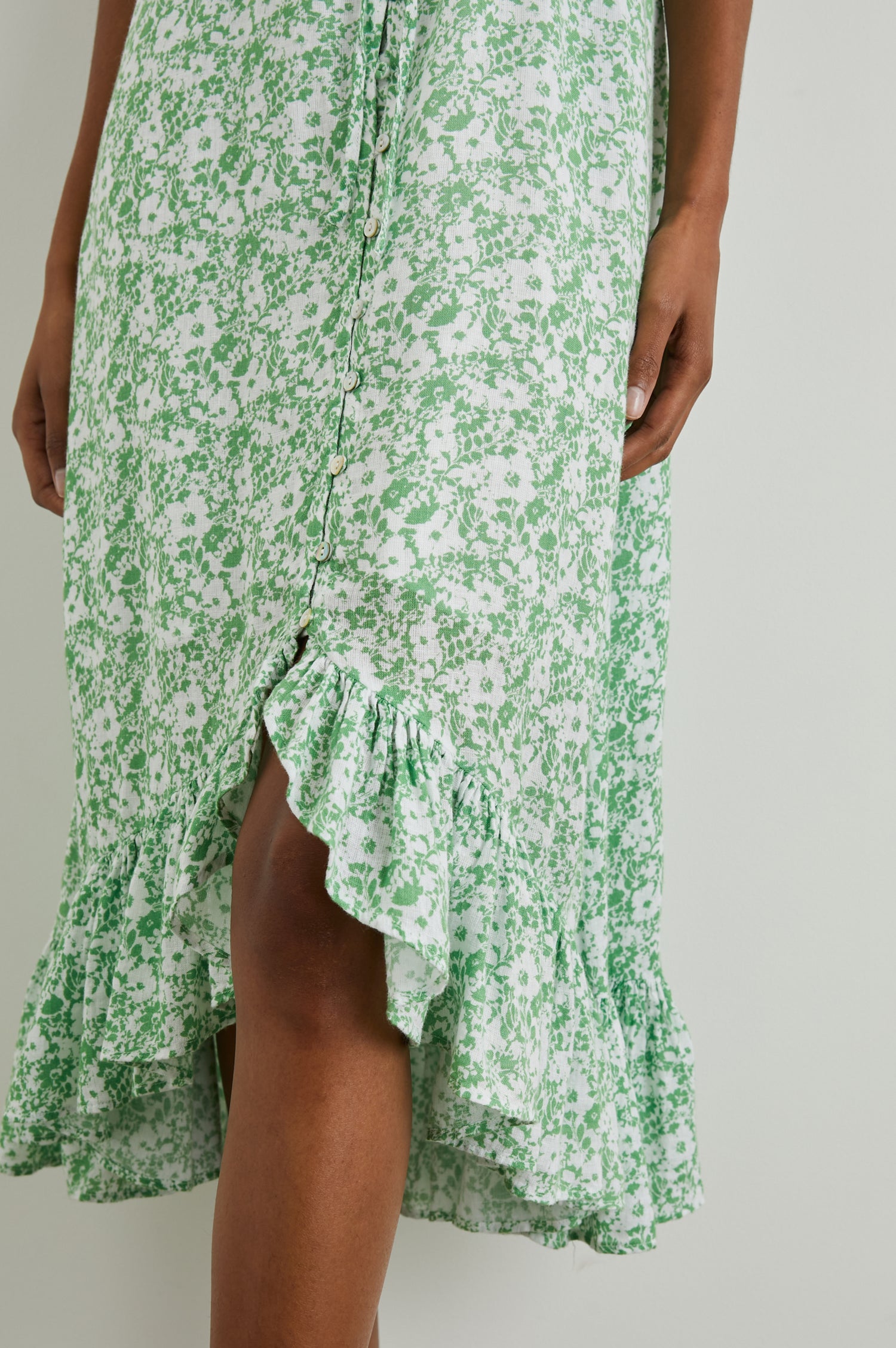 Frida Midi Dress with a Deep V Neck, Adjustable Spaghetti Straps, a Ruffled Hem, Drawstring Waist Ties and Buttons Down the Front in Green Texture Floral Colorway, Green and White Flowers - Front View Featured on Model