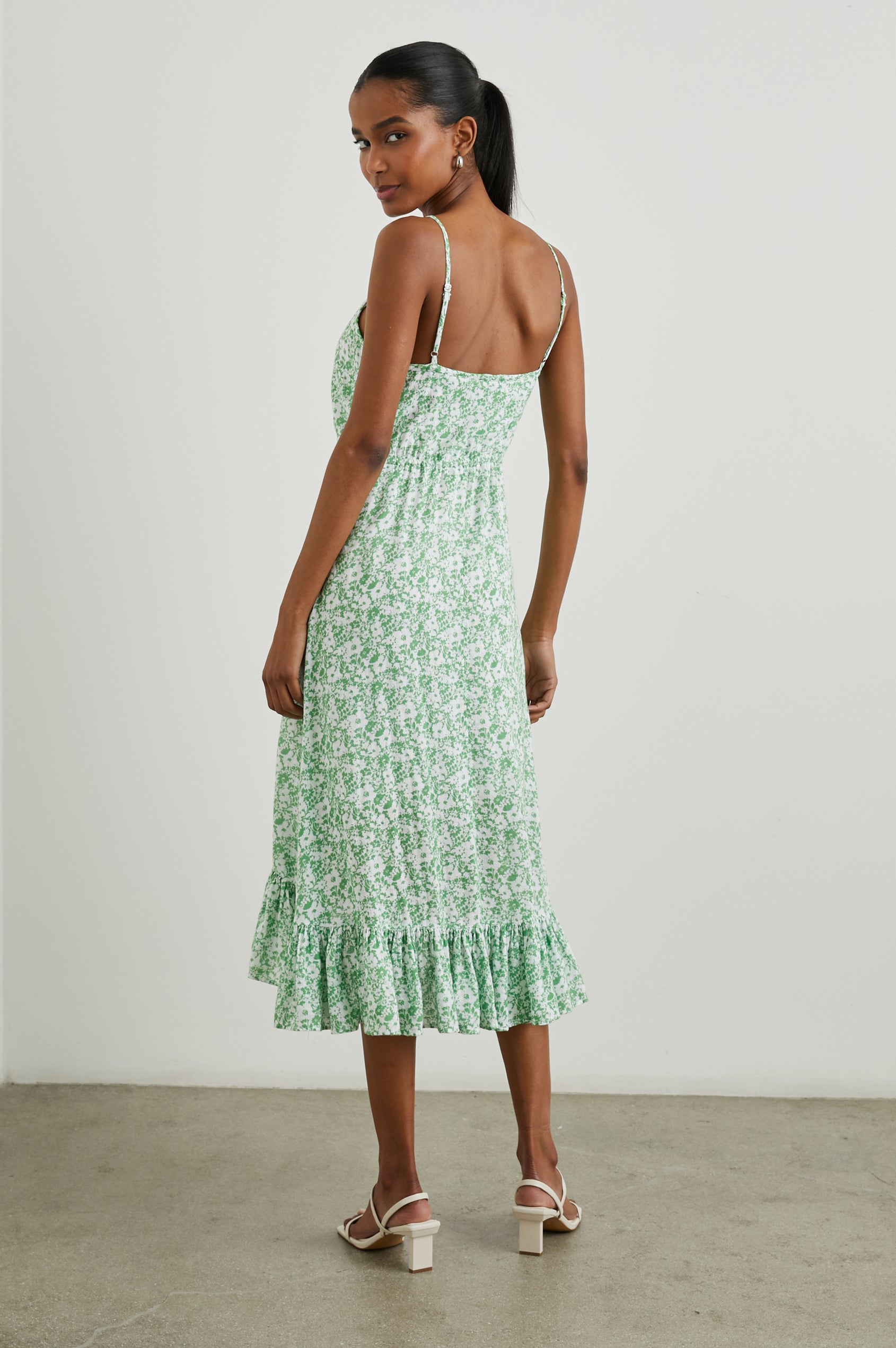 Frida Midi Dress with a Deep V Neck, Adjustable Spaghetti Straps, a Ruffled Hem, Drawstring Waist Ties and Buttons Down the Front in Green Texture Floral Colorway, Green and White Flowers - Back Full Body View Featured on Model