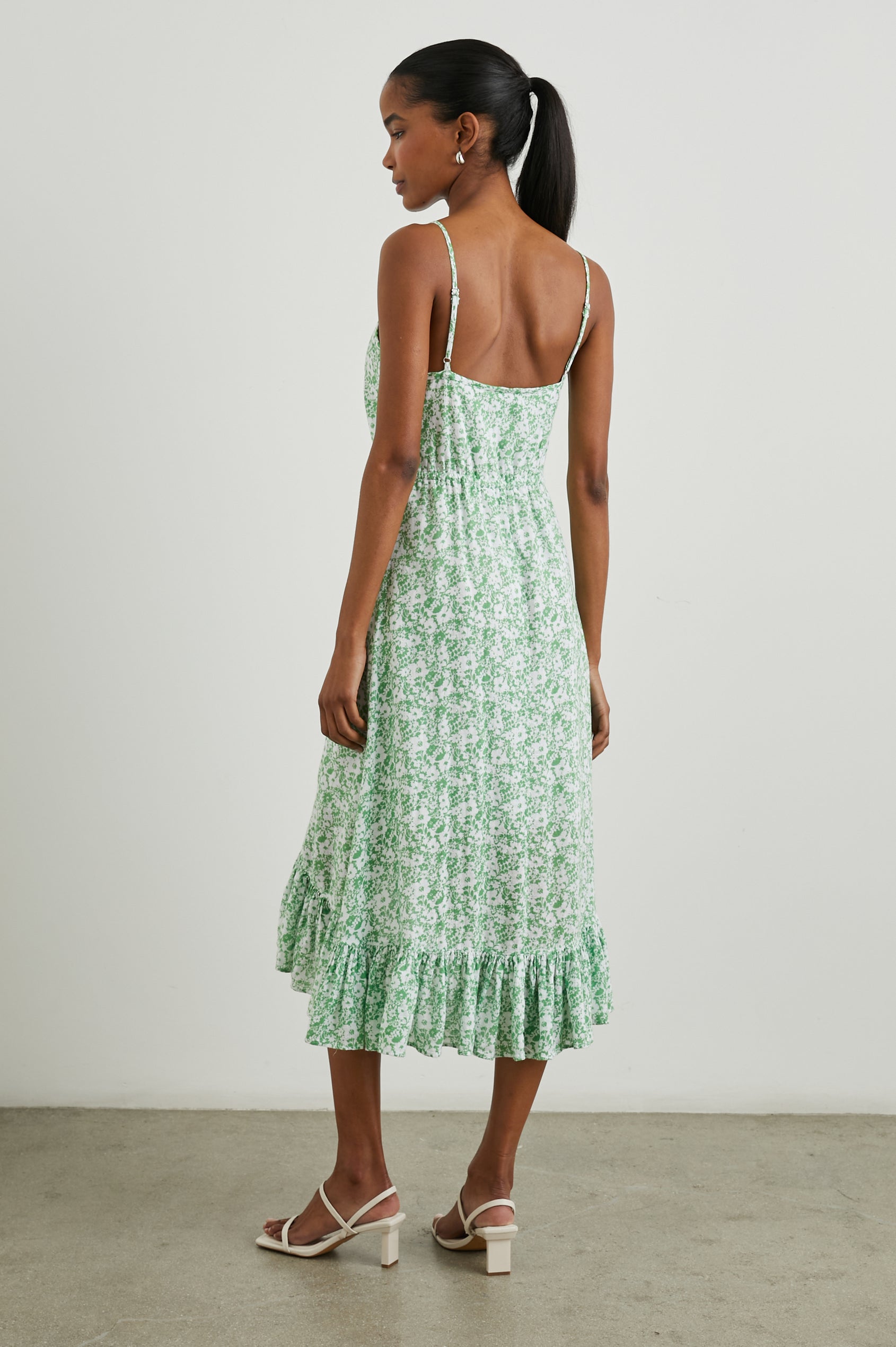 Frida Midi Dress with a Deep V Neck, Adjustable Spaghetti Straps, a Ruffled Hem, Drawstring Waist Ties and Buttons Down the Front in Green Texture Floral Colorway, Green and White Flowers - Back Full Body View Featured on Model