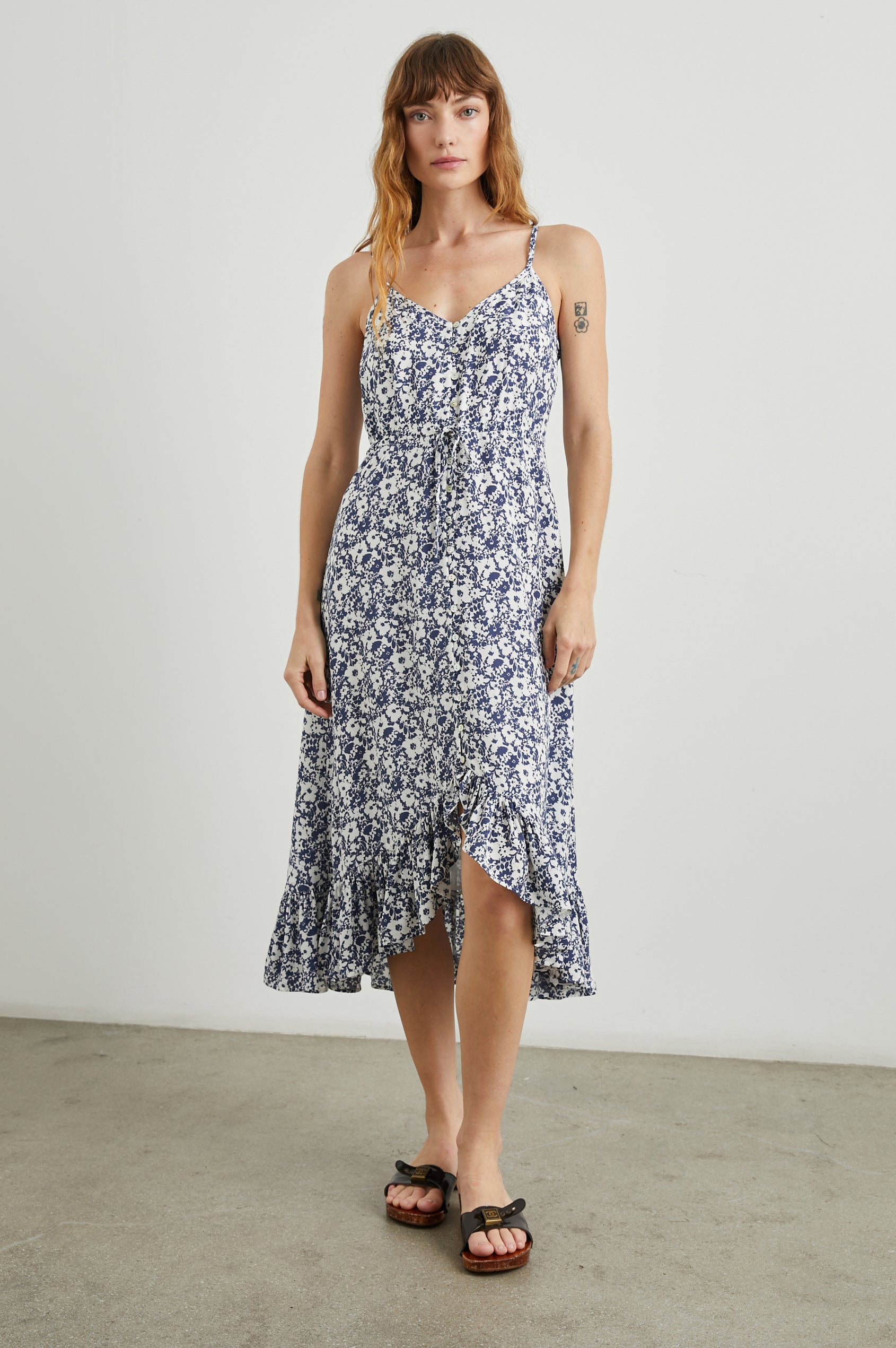 Frida Midi Dress with a Deep V Neck, Adjustable Spaghetti Straps, a Ruffled Hem, Drawstring Waist Ties and Buttons Down the Front in Navy White Texture Floral Colorway - Front Full Body View Featured on Model