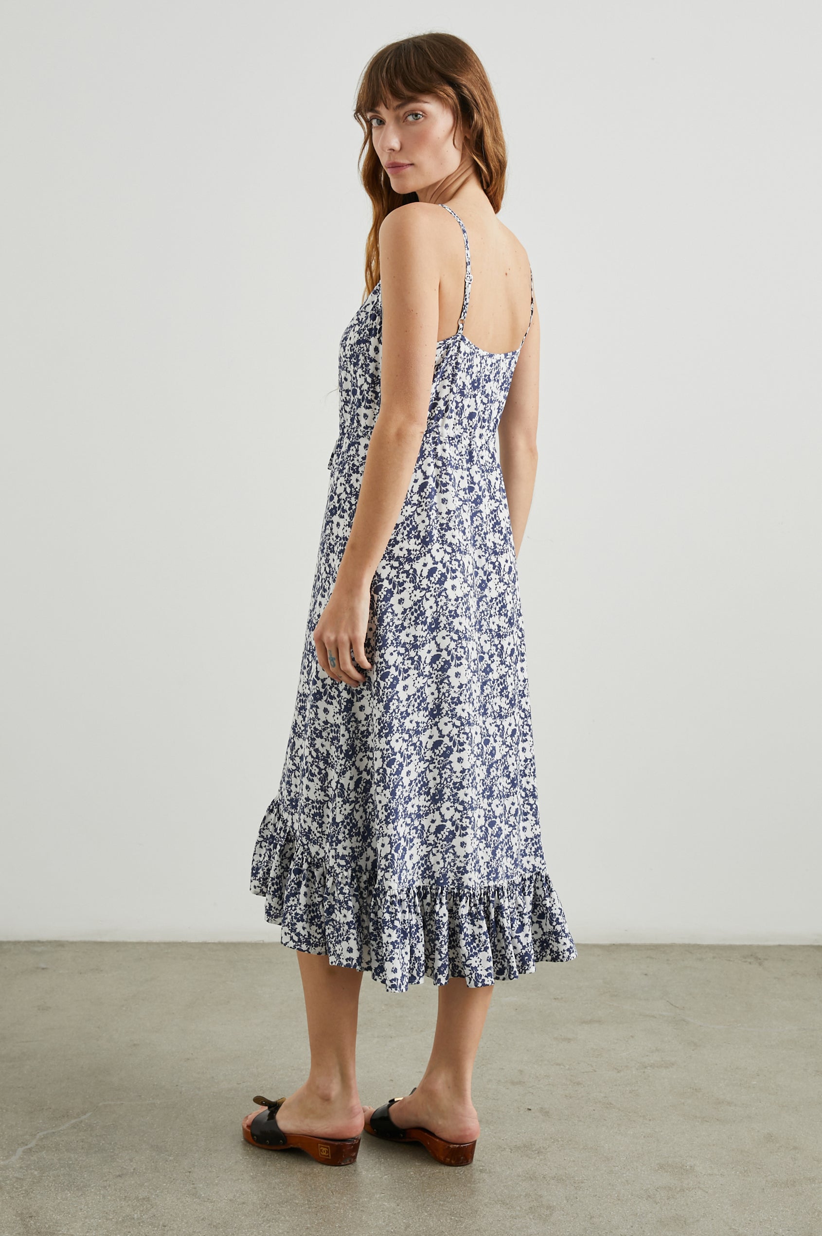 Frida Midi Dress with a Deep V Neck, Adjustable Spaghetti Straps, a Ruffled Hem, Drawstring Waist Ties and Buttons Down the Front in Navy White Texture Floral Colorway - Side Full Body View Featured on Model