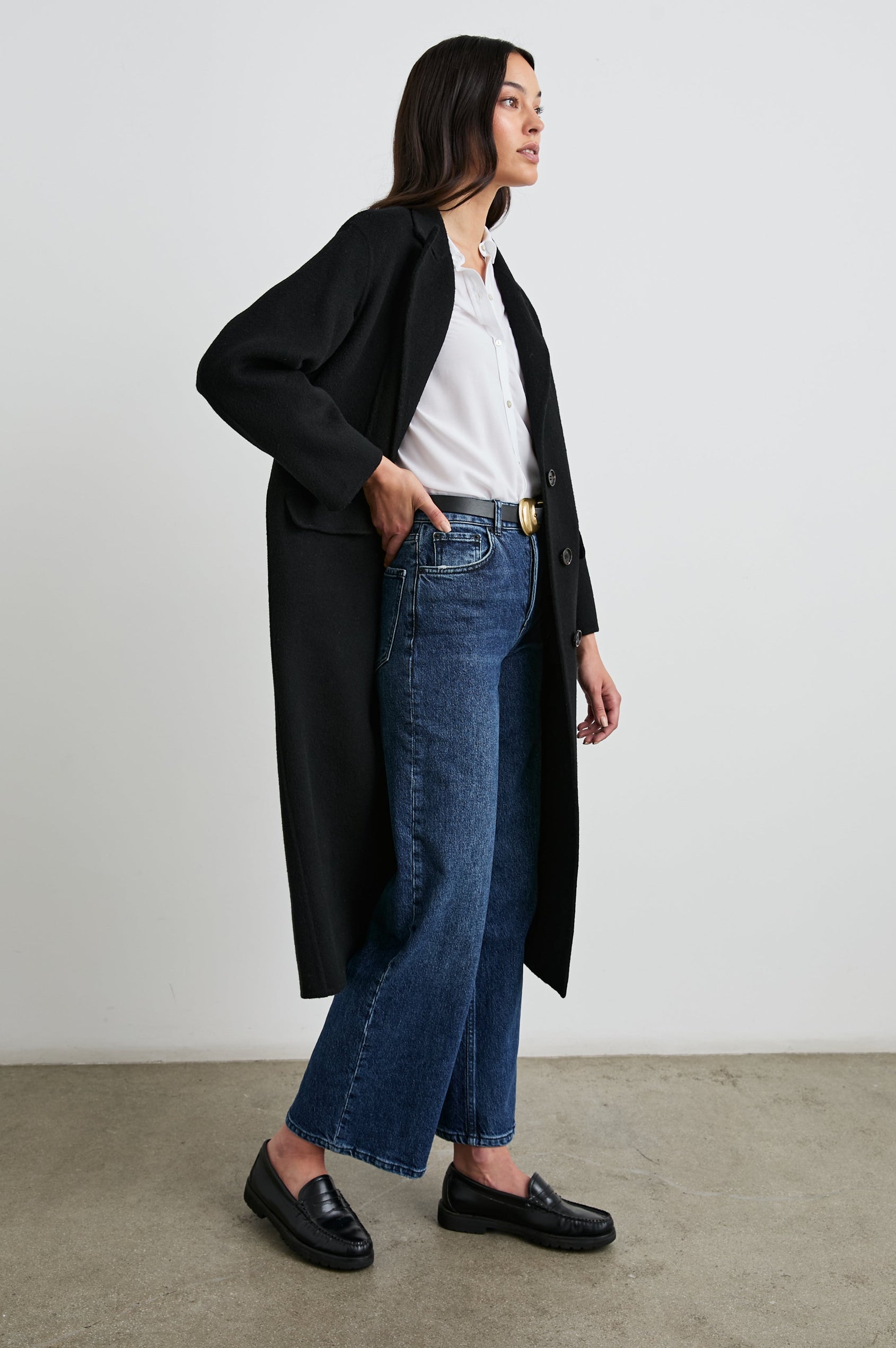 Gallery Below-the-Knee Coat with Three-Button Closure, Notched Lapels, and Two Front Flap Pockets in Black Colorway - Side Full Body View Featured on Model