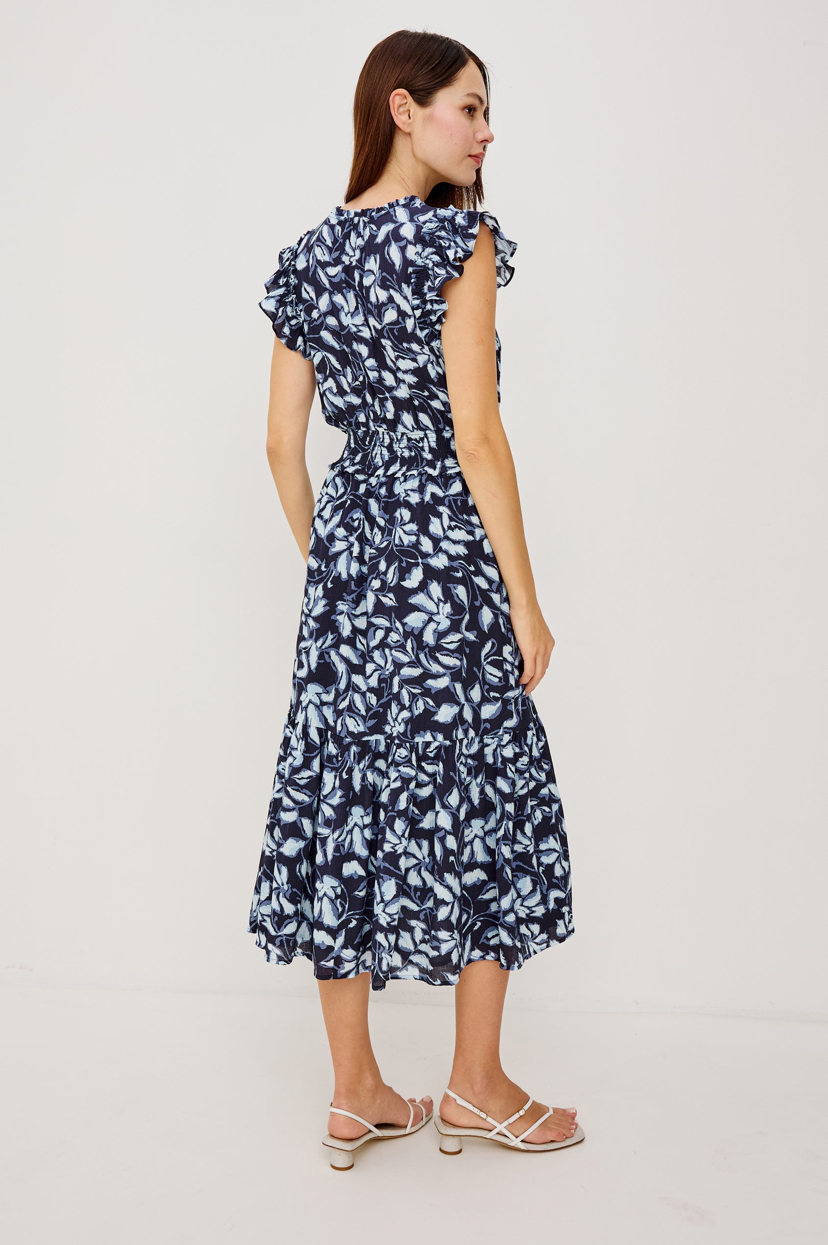 Garden Peasant Floral Midi Dress in Linen With Ruffle Flutter Sleeves, Center Front Ties, V-Neckline, Shirred Waist, and Relaxed Fit in Navy Jasmine Colorway - Full Body Back View Featured on Model