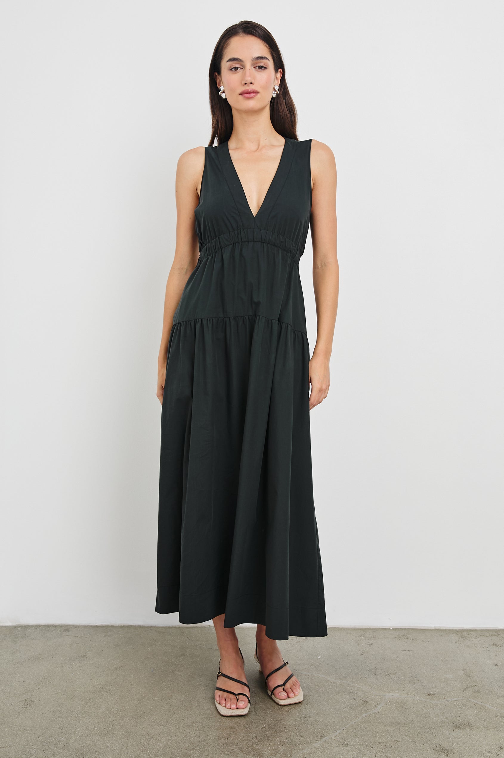 Genevieve Midi Tank Dress with Low V-Neck, Encased Elastic Waistband, Back Waist Cutout and Tiered A-Line Skirt in Black Colorway. Full Body Front View Shown on Model.