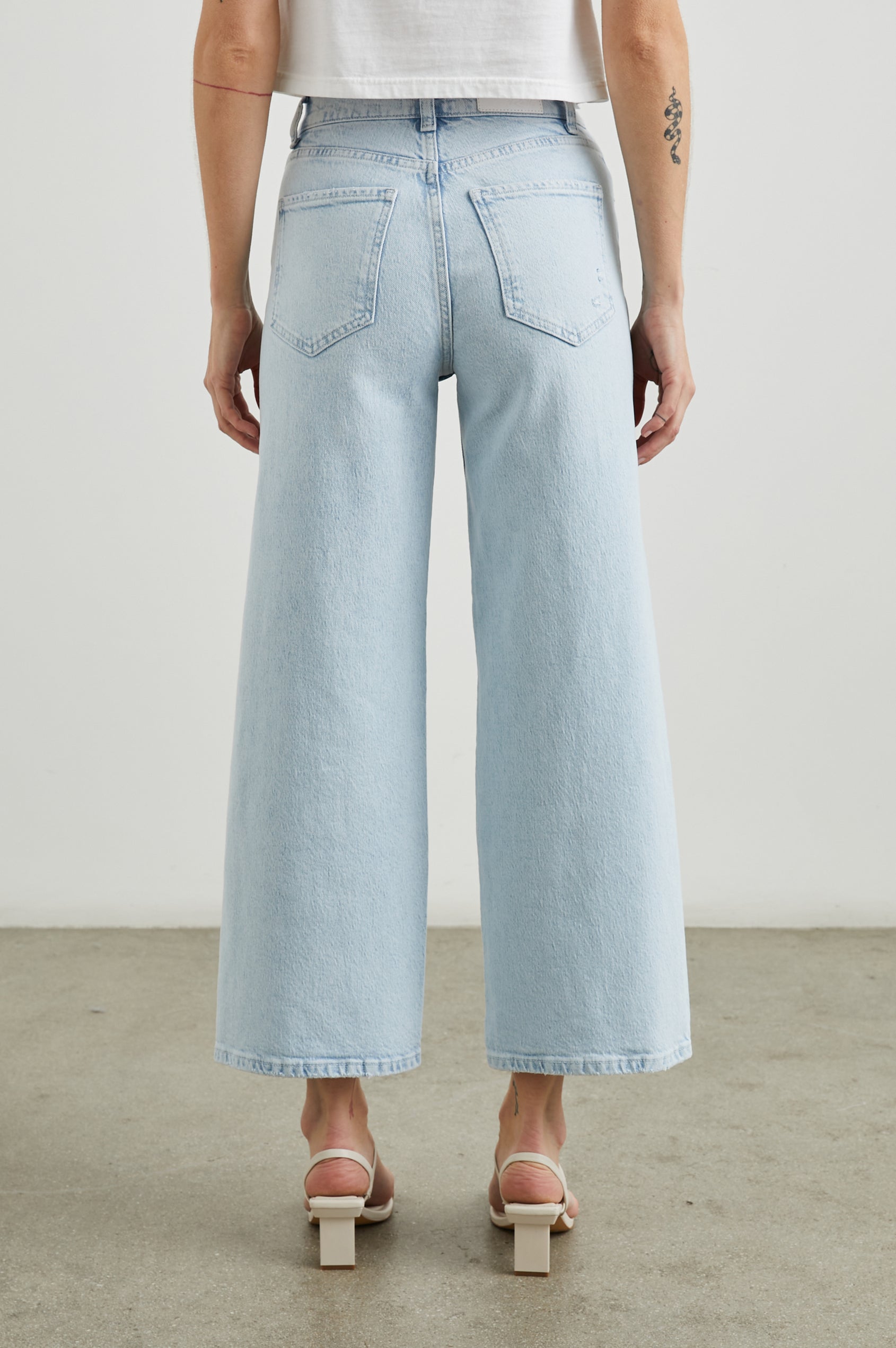 Getty Crop Wide Leg Denim Pants with Belt Loops, Fraying Near the Pockets, Two Front Pockets and Two Back Patch Pockets in Ocean Breeze Distress Colorway - Back View Featured on Model