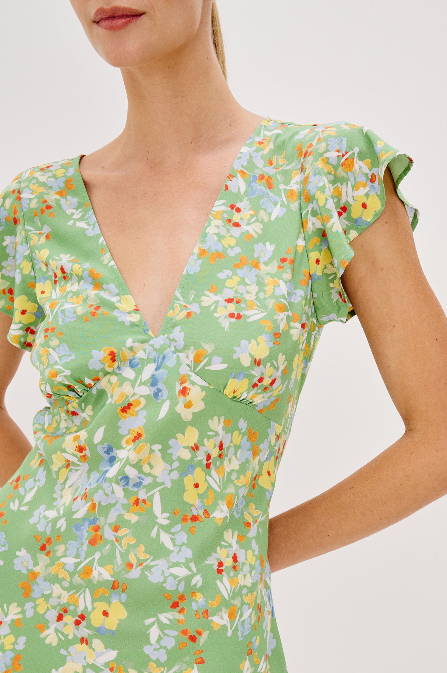 Gigi V-Neck Mini Dress with Short Flutter Sleeves, Empire Waist  in Green Meadow Colorway. Front Detail View Shown on Model.