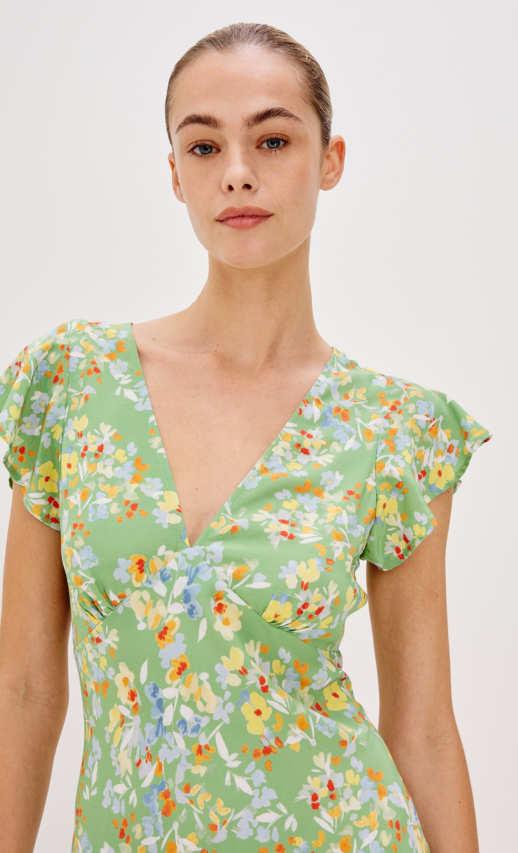 Gigi V-Neck Mini Dress with Short Flutter Sleeves, Empire Waist  in Green Meadow Colorway. Front View Shown on Model.