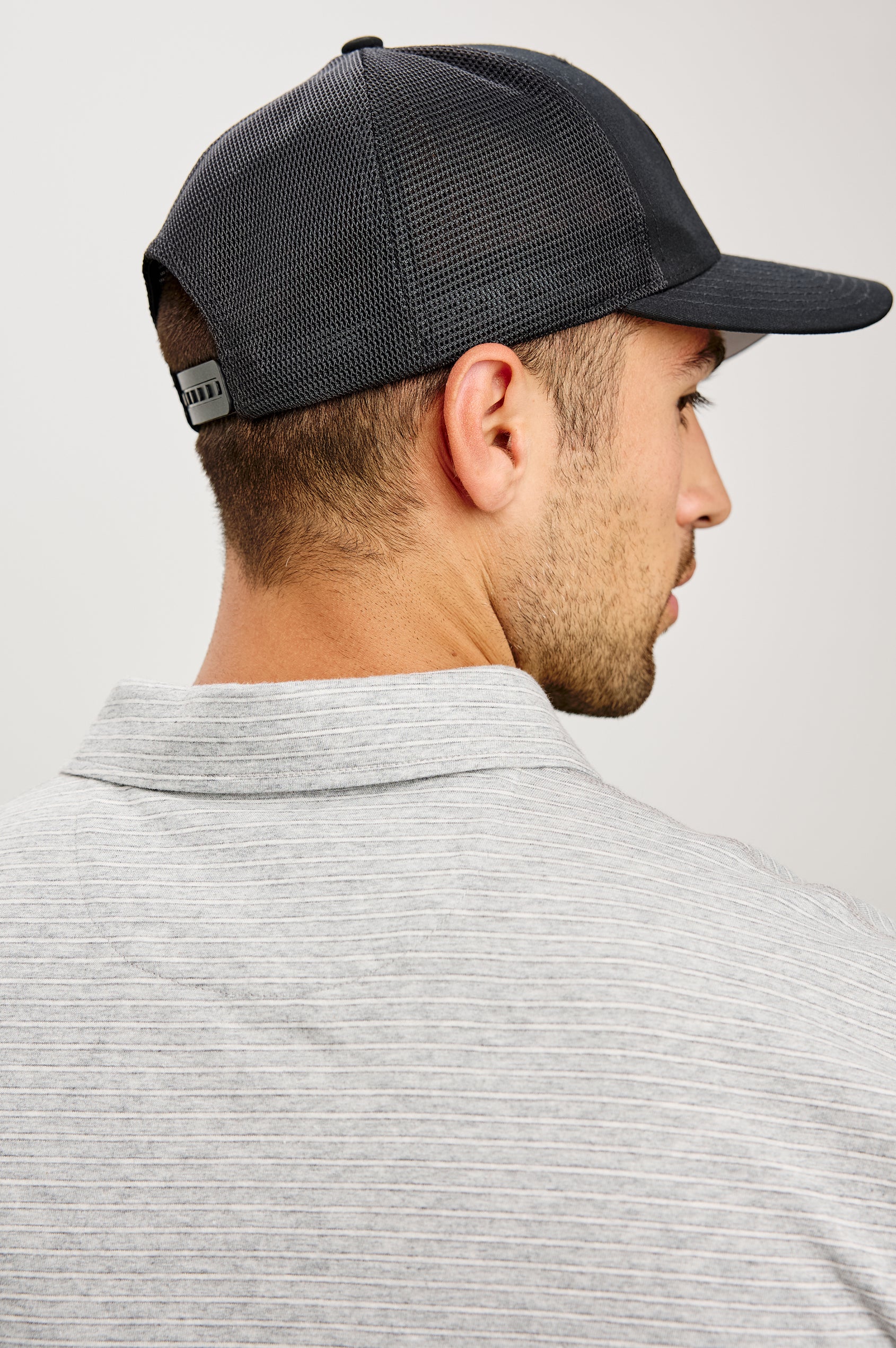 Golf Hat With Embroidered Branded Patch at Front, Adjustable Snapback, Mesh Back, and 6-Panel Construction in Black Colorway - Upper Body Back View Featured on Model