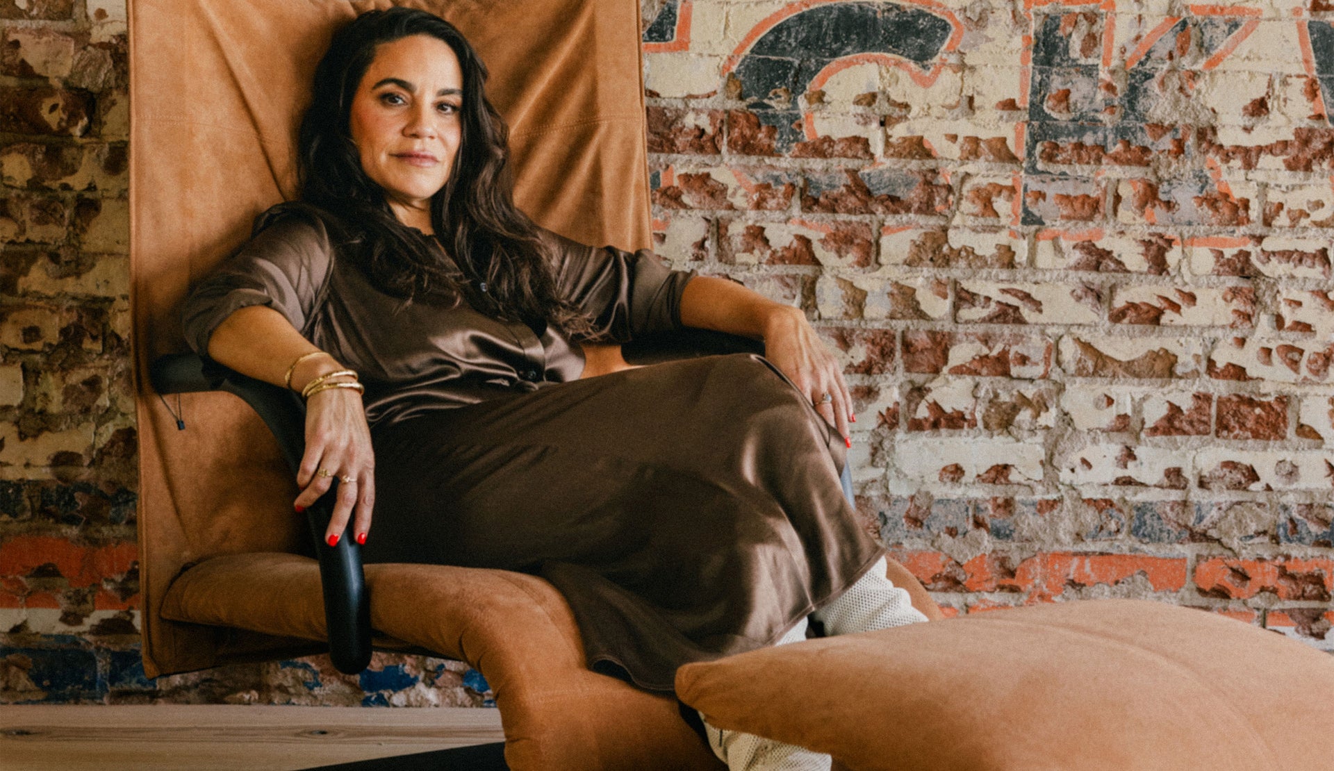 FEMALE SITTING WEARING ANINA DRESS (LONG SLEEVE SHIRT DRESS WITH BUTTONS UP THE FRONT OF THE DRESS AND TIE WAIST) IN COLOR  DARK MOSS (BROWN)