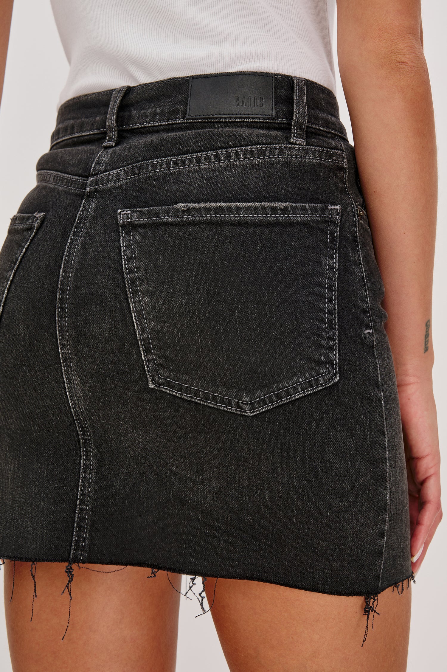Highland 5-Pocket Denim Mini Skirt with Standard Zip + Button Fly, Raw Hem in Black Spellbound Colorway. Back Detail View Shown on Model.