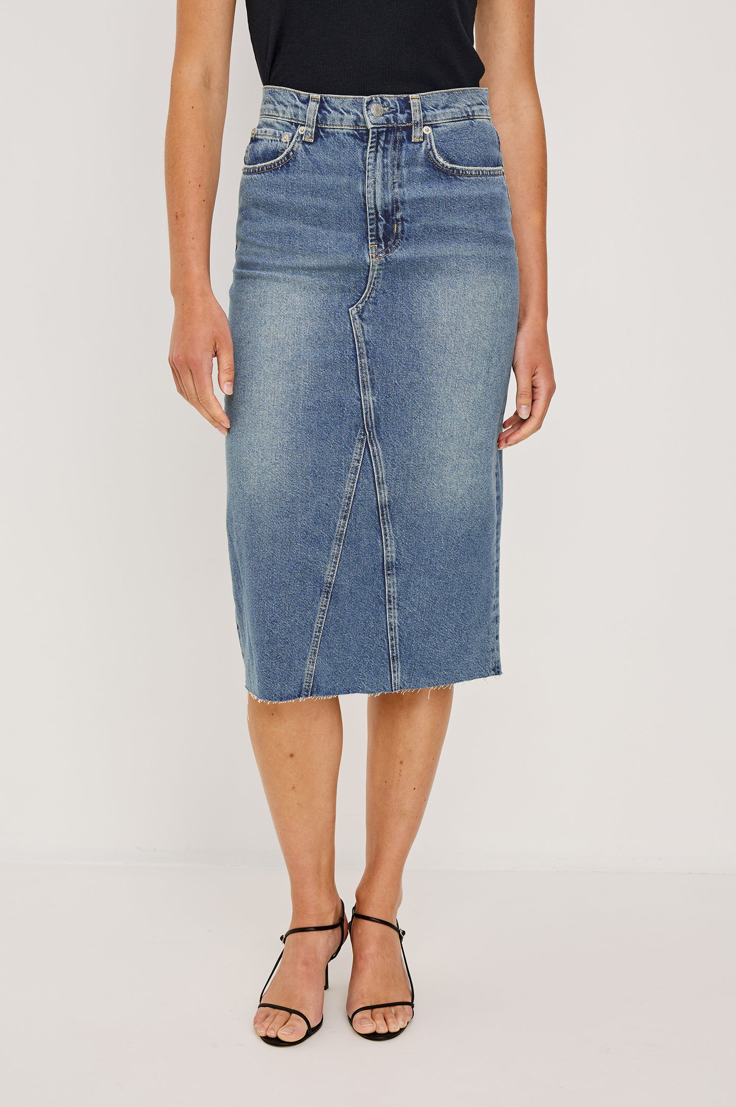 Highland Denim Midi Skirt with a Raw Hem, a Back Vent, Additional Front Seams, Belt Loops, Two Front Pockets plus a Coin Pocket and Two Back Patch Pockets in Vintage Sapphire Colorway - Front View Featured on Model 