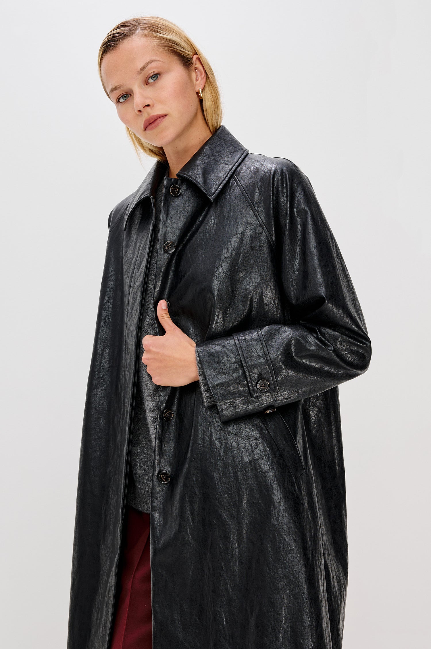 Hills Knee-Length Faux Leather Jacket with Button Closure, a Hidden Placket, Two Front Pockets, and Button Tabs at the Cuffs in Black Colorway - FrontView Featured on Model 
