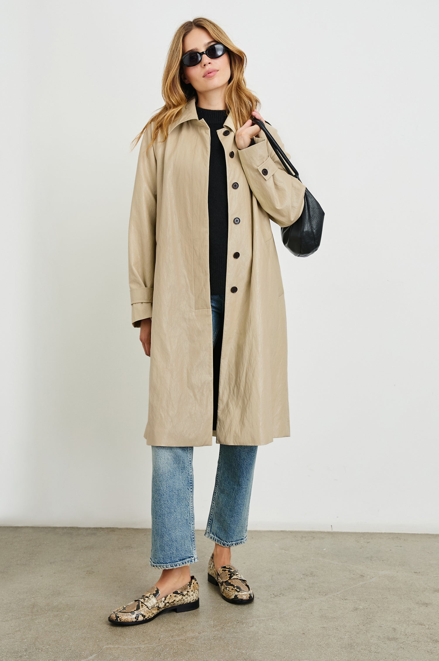 Hills Knee-Length Faux Leather Jacket with Button Closure, a Hidden Placket, Two Front Pockets, and Button Tabs at the Cuffs in Dune Colorway - Front Full Body View Featured on Model 