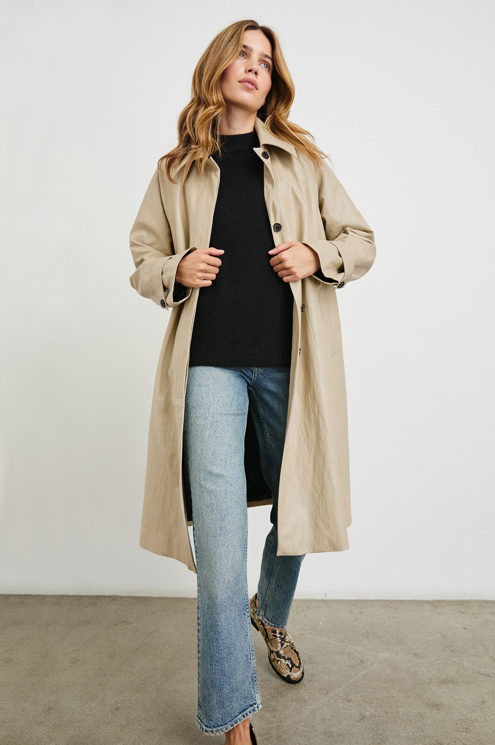 Hills Knee-Length Faux Leather Jacket with Button Closure, a Hidden Placket, Two Front Pockets, and Button Tabs at the Cuffs in Dune Colorway - Front Full Body View Featured on Model 