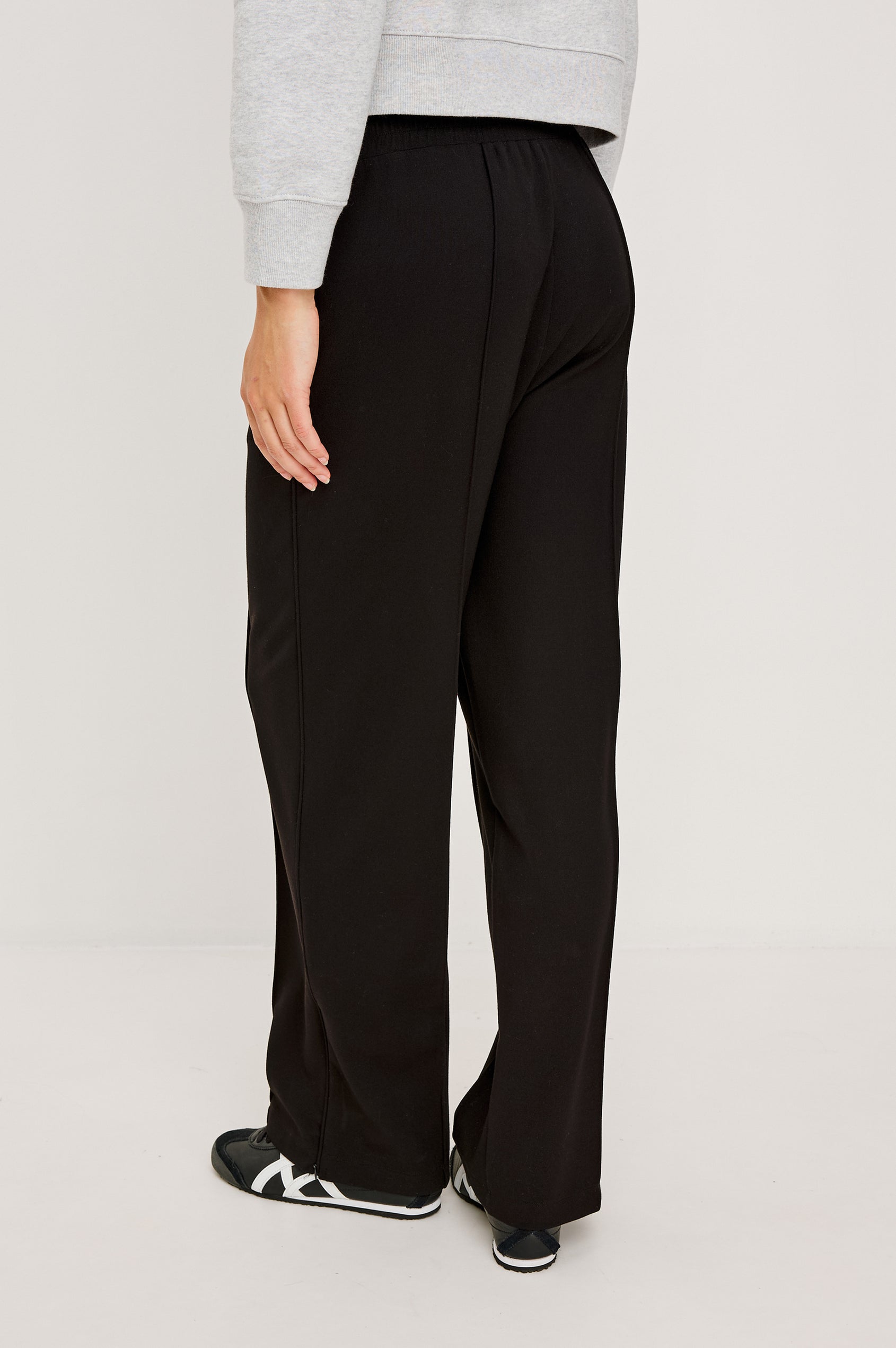 Black ponte pull-on pants with an elastic waistband. The pants feature functional ankle zippers that can be opened to create a subtle flare. Back View on Model.