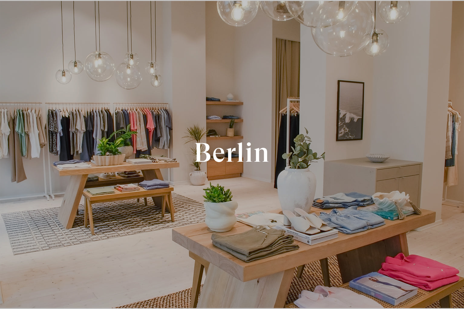 INSIDE OF BERLIN STORE SHOWING MULTIPLE TABLES IN THE MIDDLE OF THE ROOM WITH CLOTHING FOLDED ON TOP OF THEM