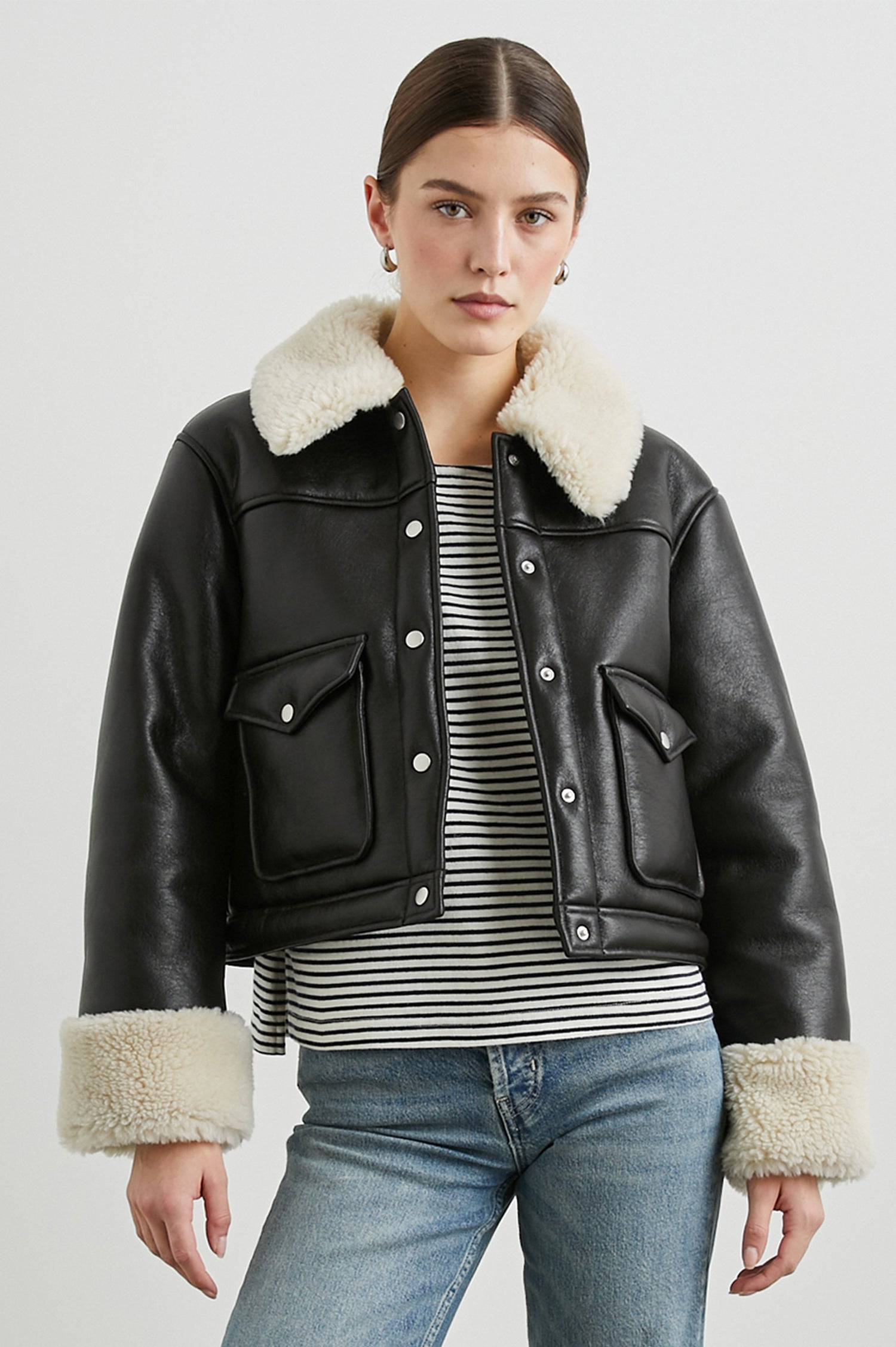 Imani Cropped Faux Leather Jacket with Silver-Toned Snap Closure, Two Front Snap Flap Pockets and Ivory Faux Shearling Lining, Collar and Cuffs in Black Ivory Colorway - Front View Featured on Model  