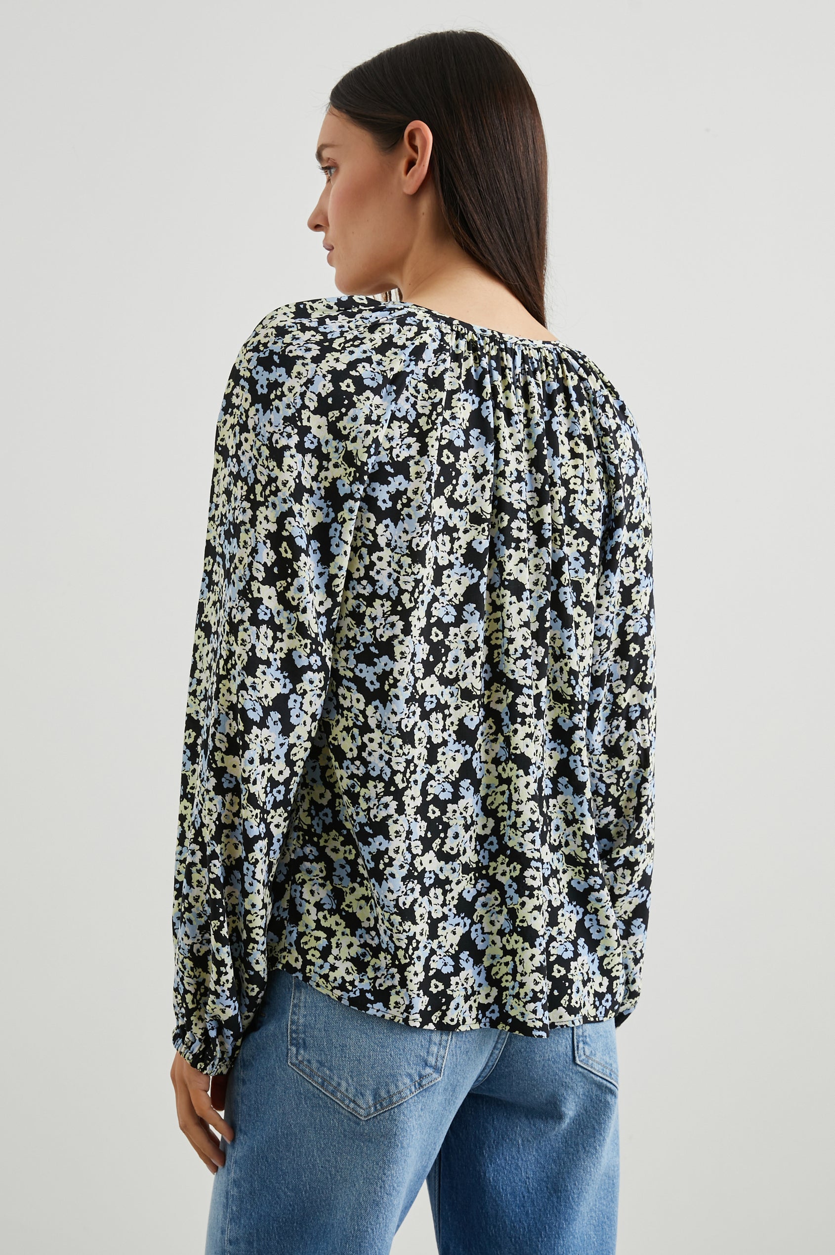 Indi Top with a V Neckline with a Button Placket, Pleating at Back Neckline and Elastic Cuffs in Midnight Meadow Floral Colorway, with cream and blue flowers on  midnight - Back View Featured on Model