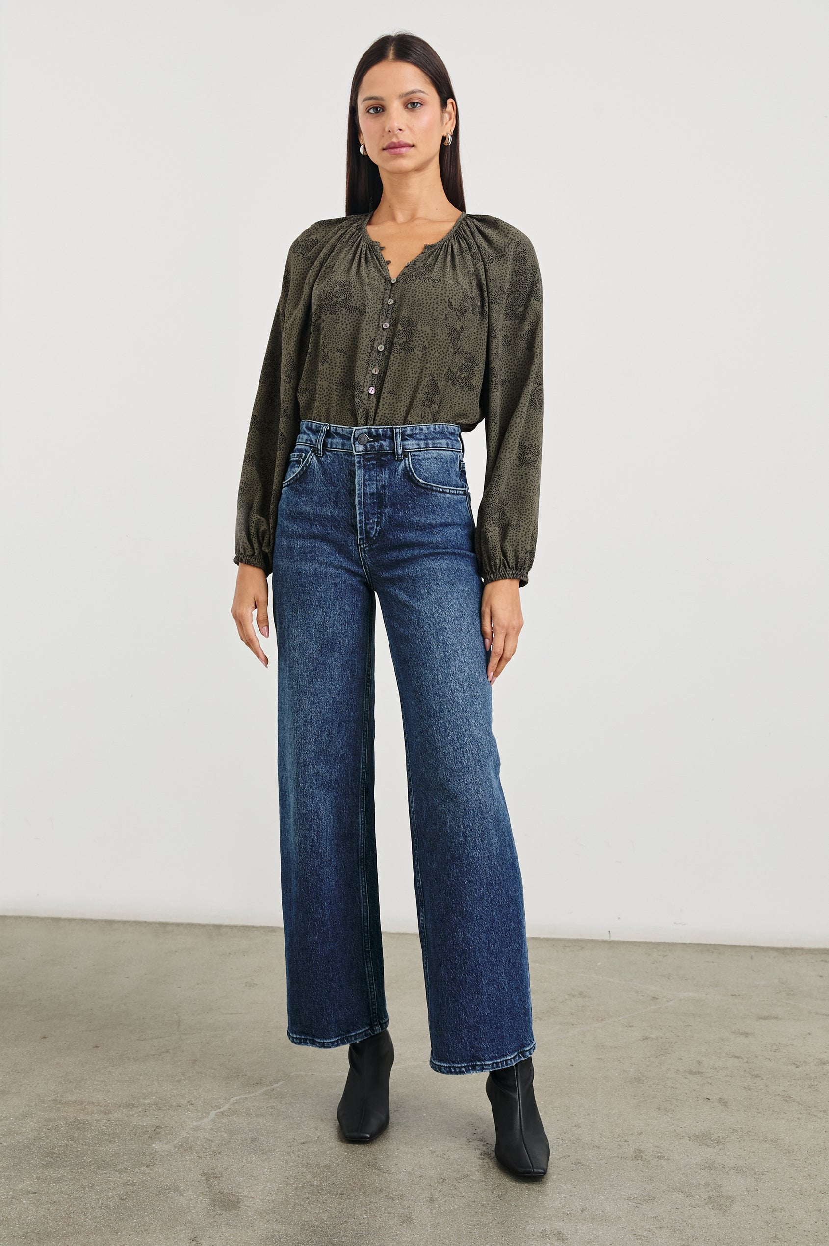 Indi Top with a V Neckline with a Button Placket, Pleating at Back Neckline and Elastic Cuffs in Olive Pebble Colorway, with black pebbles on olive - Front tucked Full Body View Featured on Model