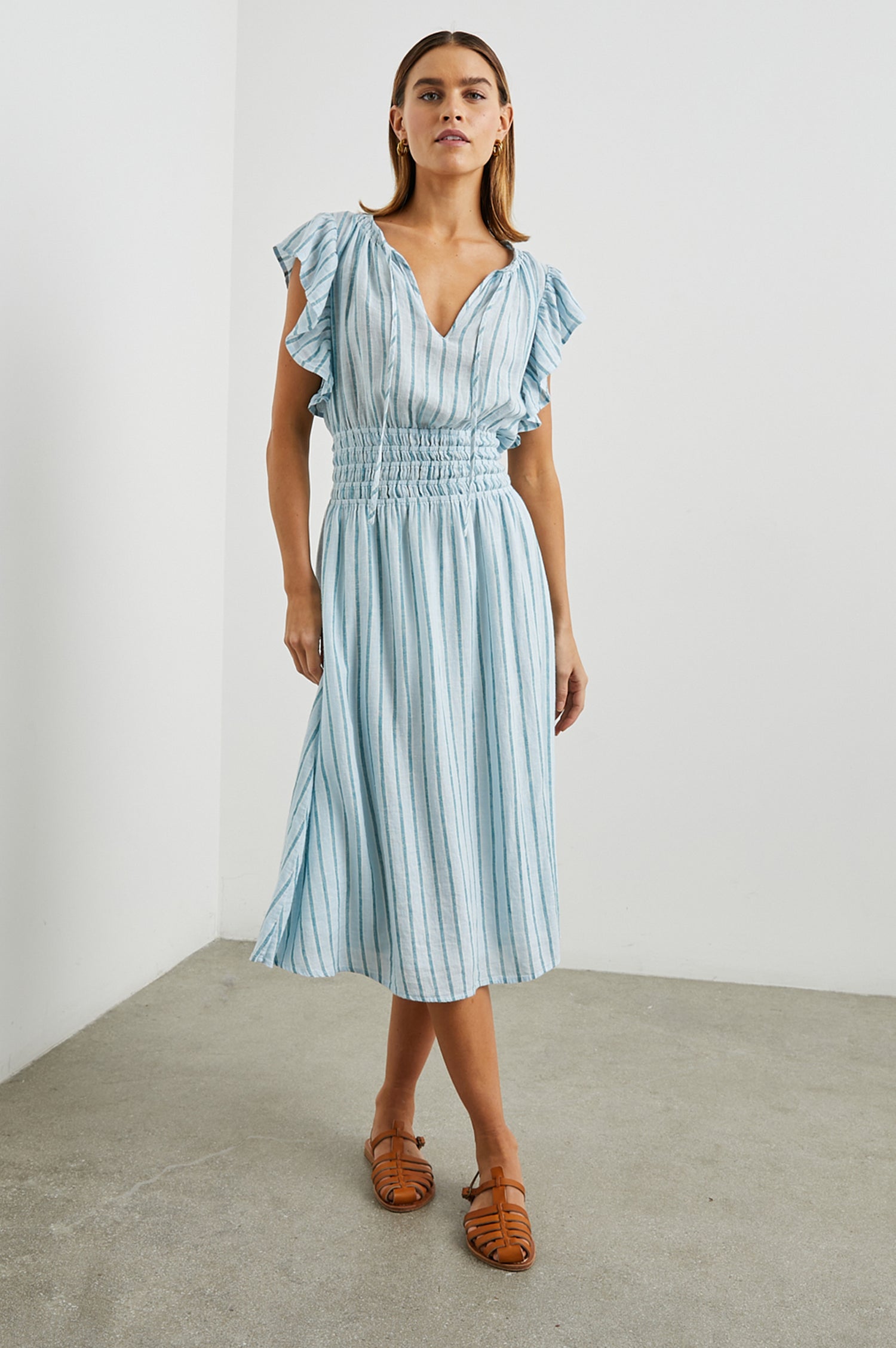 Iona Short Sleeve Midi Dress with Flutter Sleeves, a Deep V Neck with Ties, and a Shirred Waist in Cambria Stripe Colorway, Vertical Stripes in White, Blue and Light Blue - Front Full Body View Featured on Model 