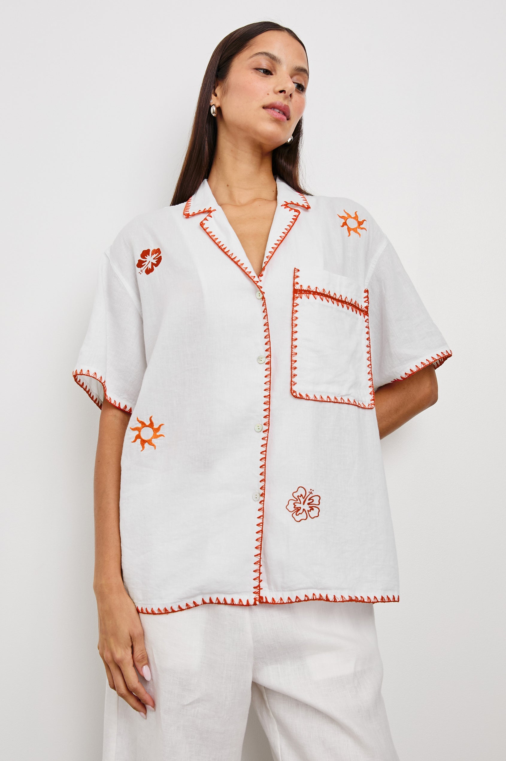 Island Short-Sleeve, Button-Down Shirt with Flat Collar, Large Chest Patch Pocket, Embroidered Decorative Trim and Embroidered Flowers and Sun in Red and Yellows in White Colorway - Front View Featured on Model 
